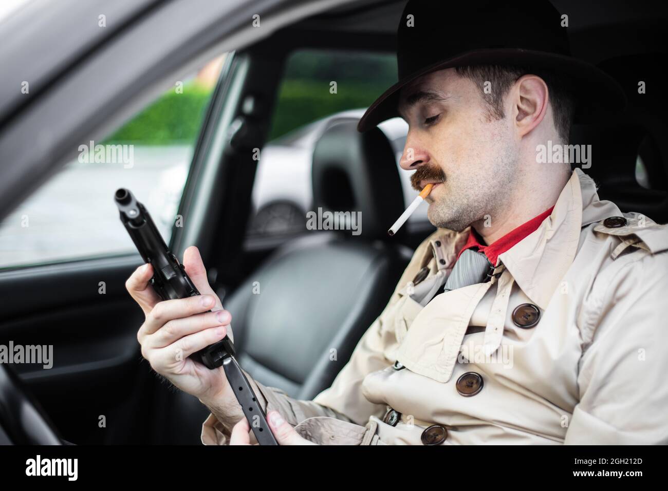 Detective readying his gun while waiting in his car Stock Photo