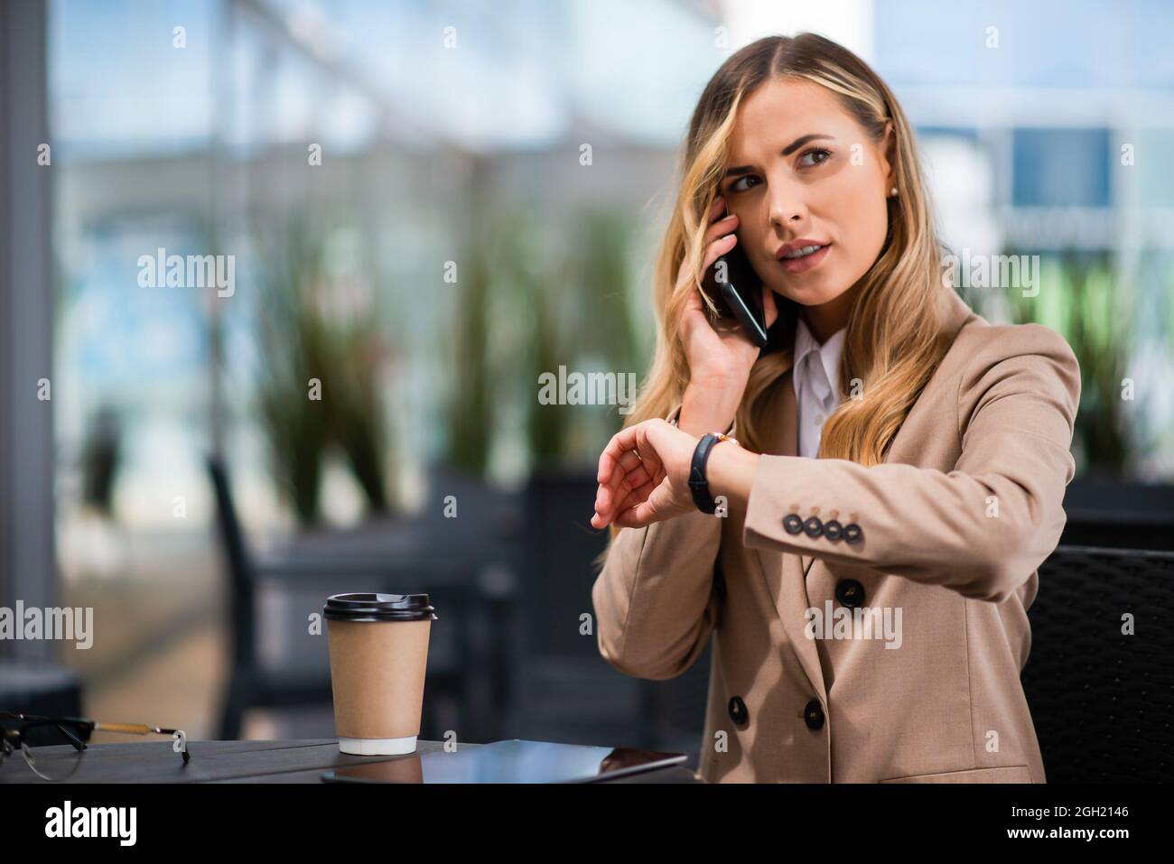 Woman looking at her watch while talking on her cellphone Stock Photo