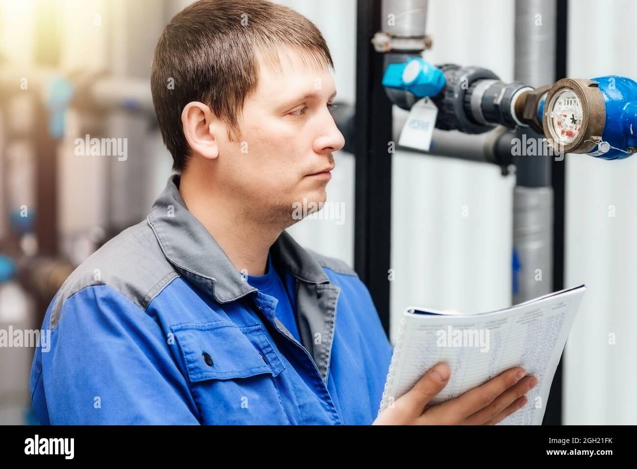 Engineer, worker registers readings of sensors and pressure gauges. Control of water supply and heating system. Checking the equipment before the start of the heating season Stock Photo
