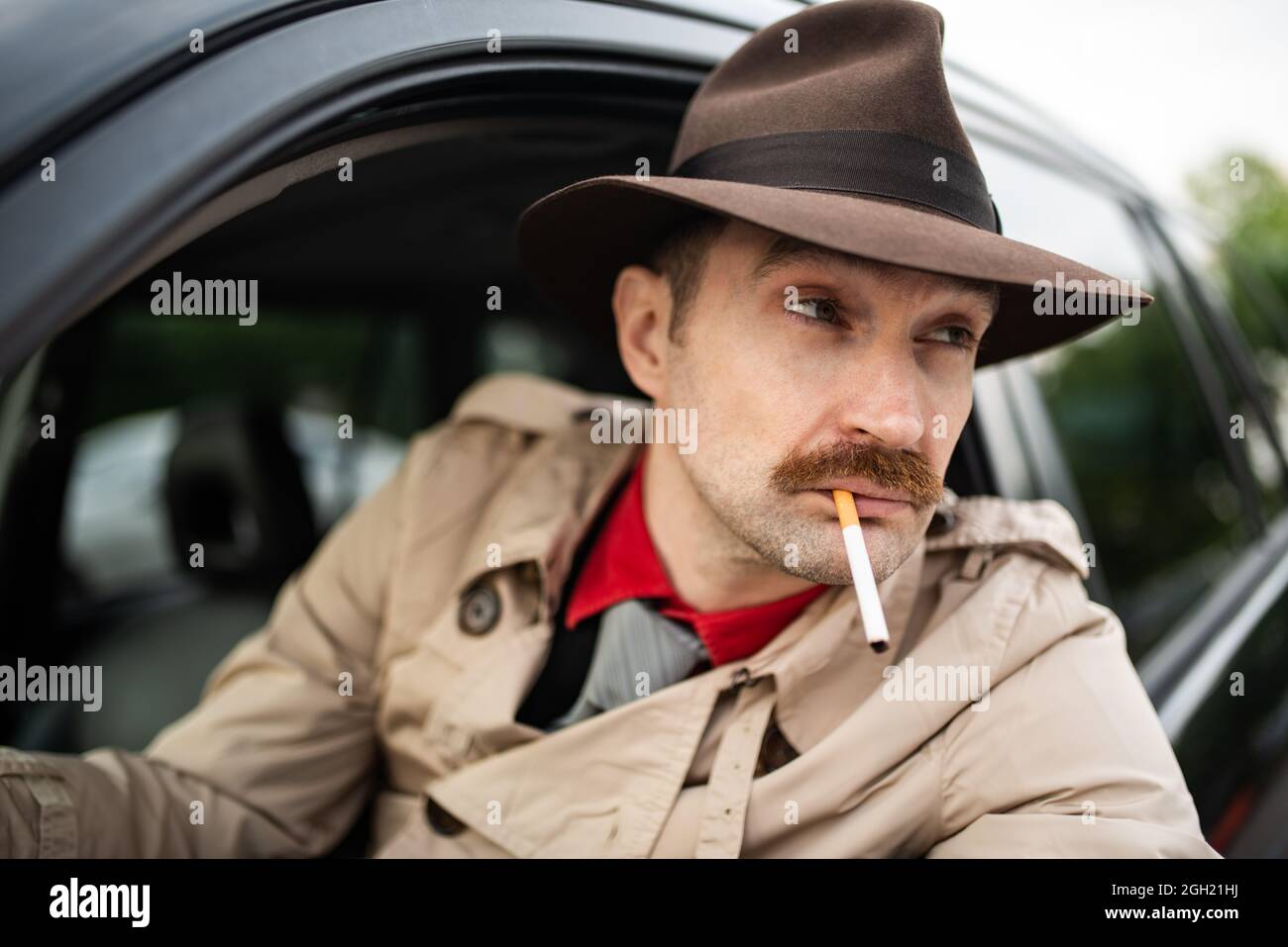 Detective smoking a cigarette in his car while stalking Stock Photo