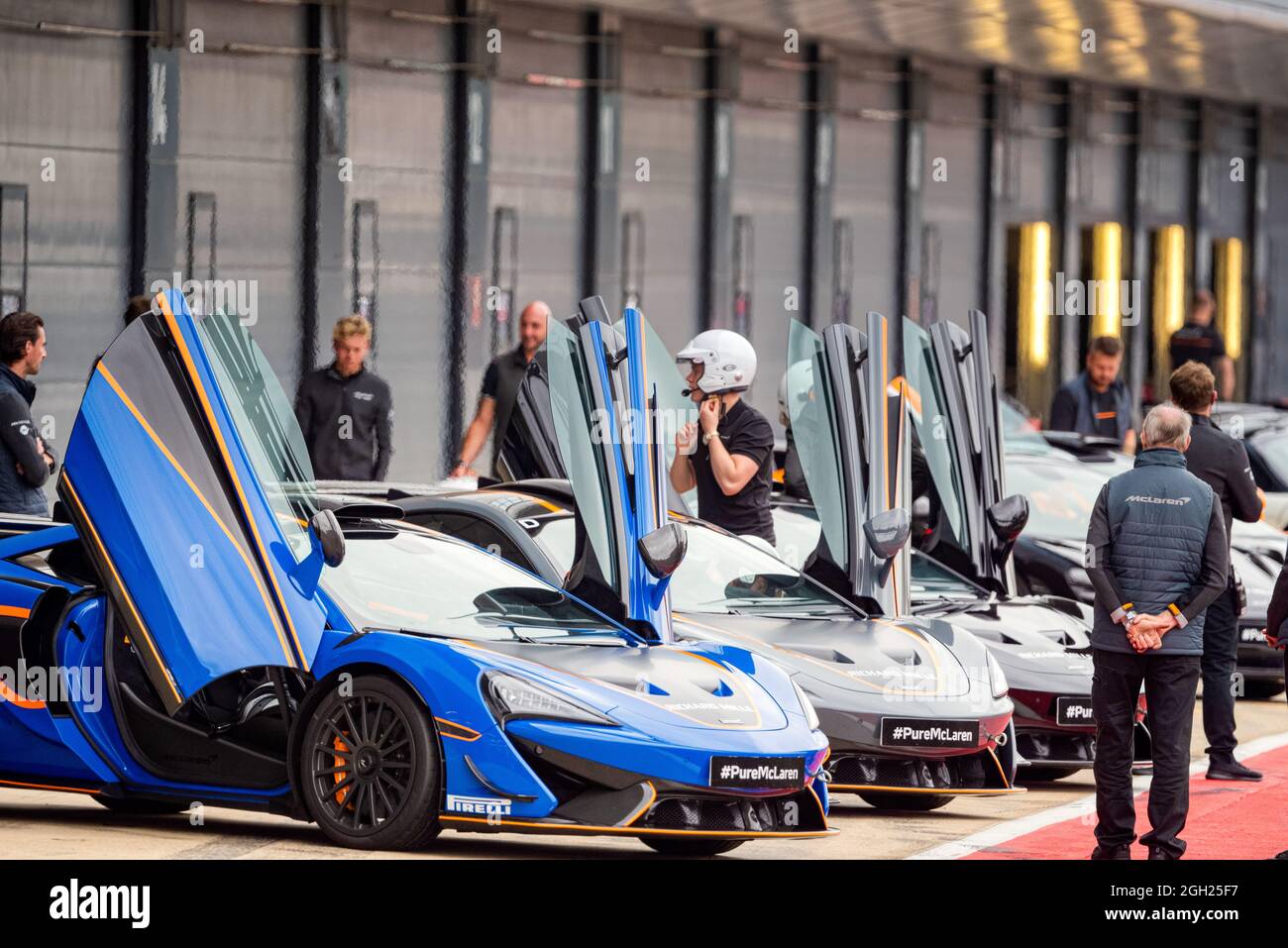 Doors open on McLaren supercars lined up in the pit lane at the