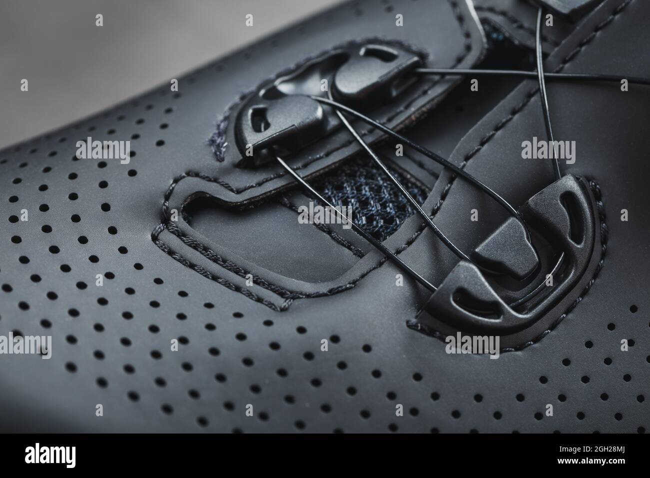 Sports shoes made of black perforated leather in a dark key. Close-up Stock Photo