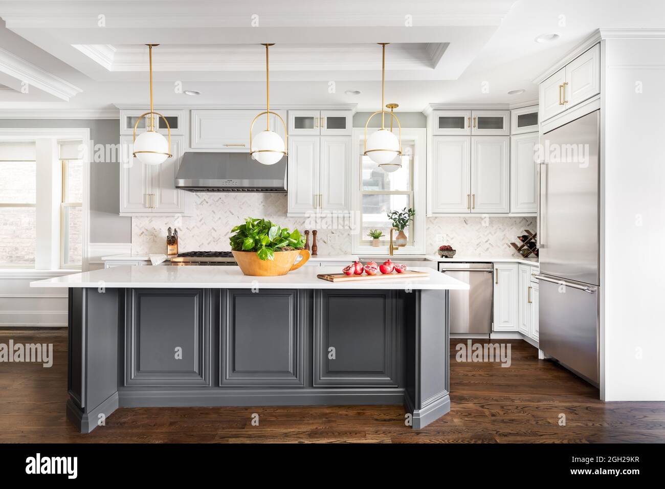A luxurious white and grey kitchen with a large island, stainless steel