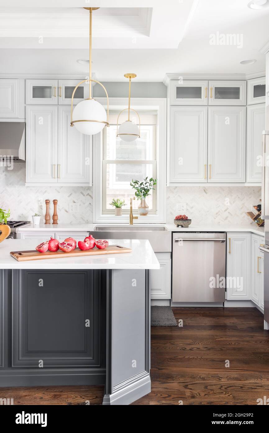 A luxurious white and grey kitchen with a large island, stainless steel