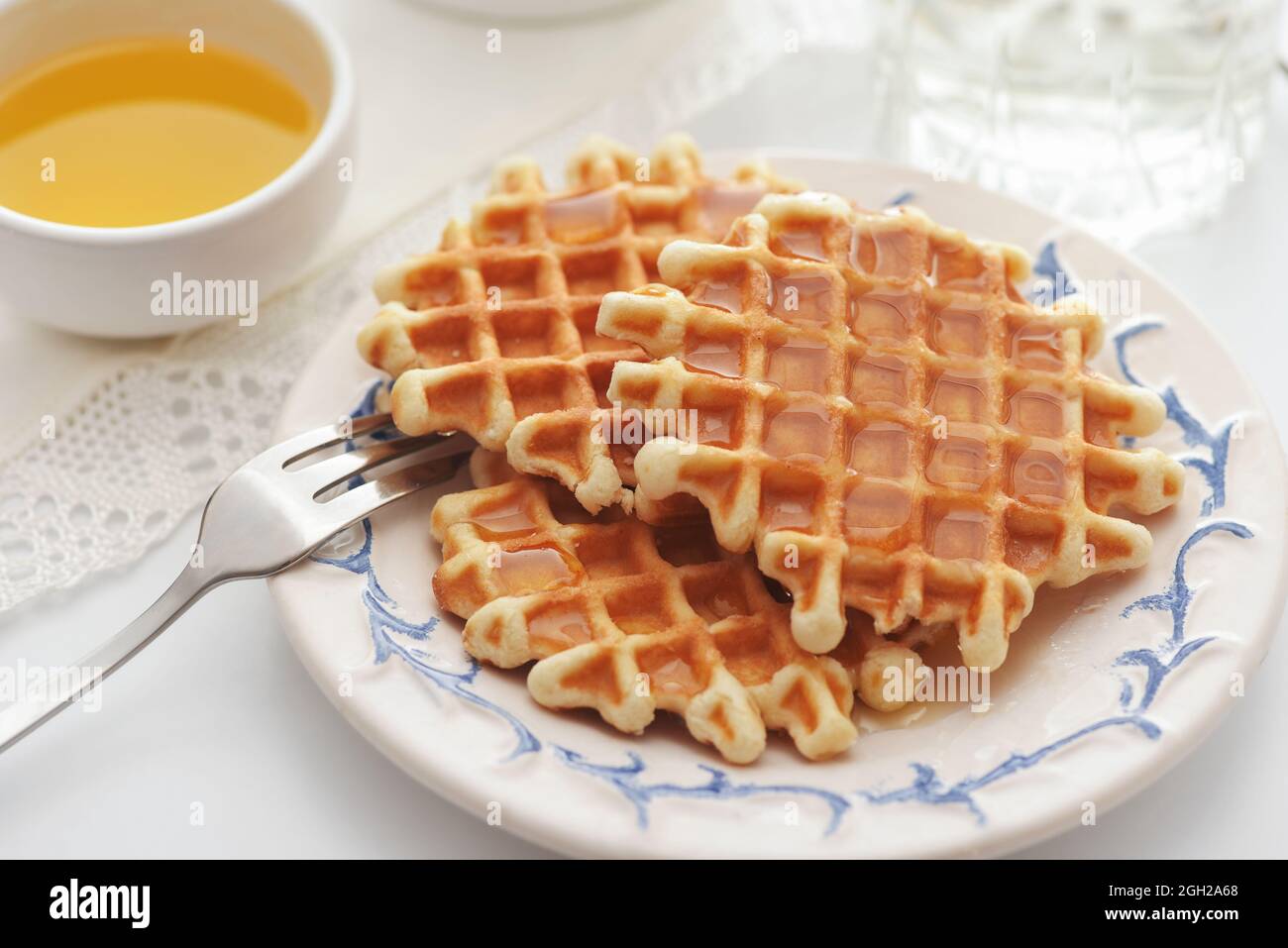 Freshly baked homemade belgian waffles with honey on white table Stock Photo