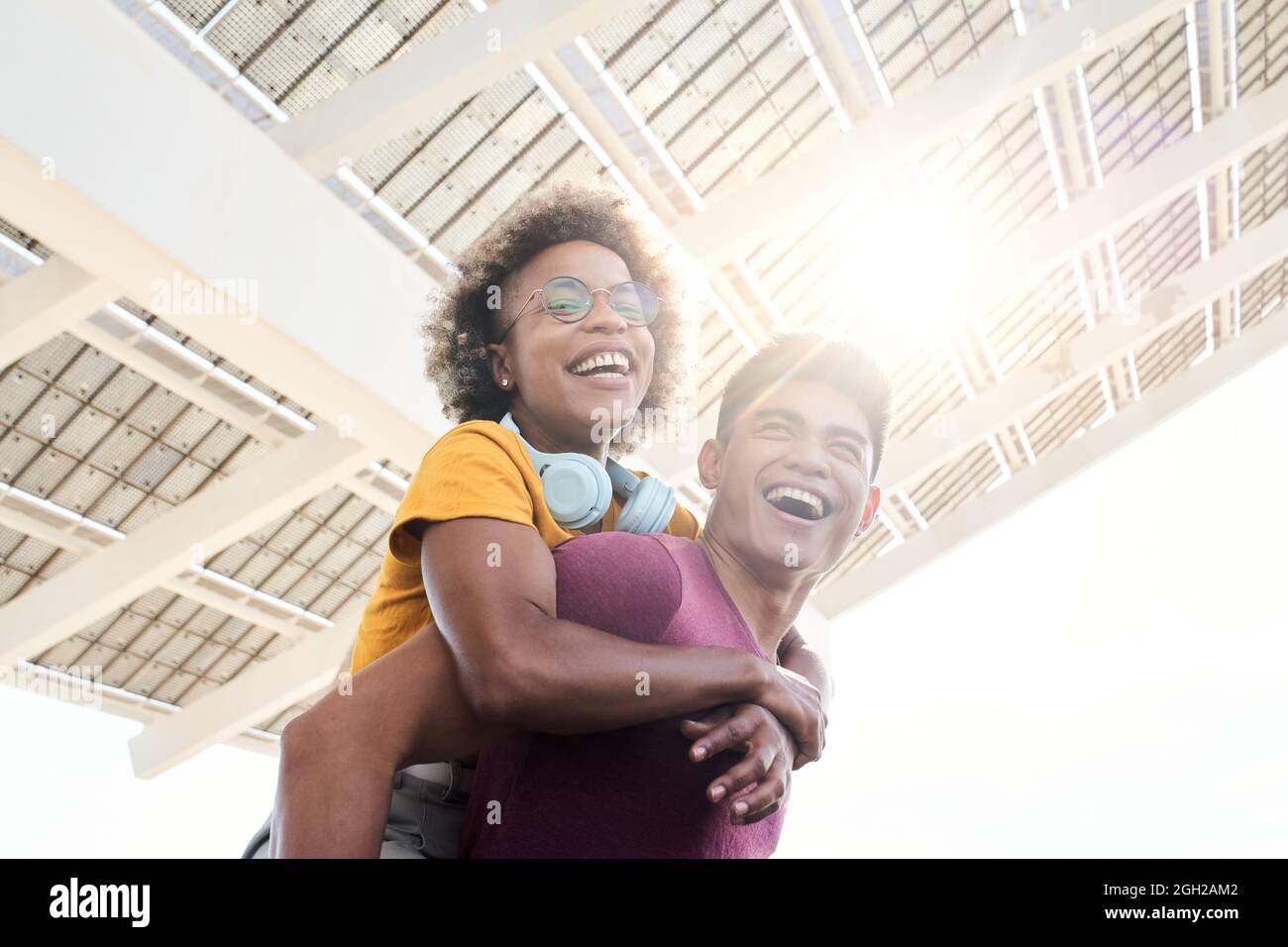 Young smiling lovers looking at the camera. The girl is piggyback on her boyfriend. Concept of friendship and couple relationship having fun. Stock Photo