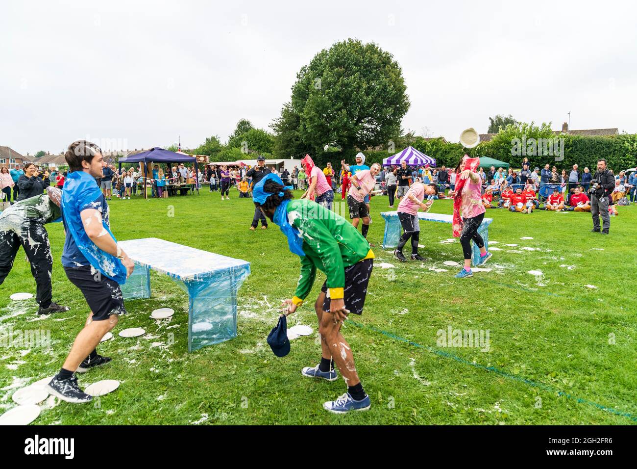 Two teams of four each in fancy dress, in a field, throwing custard ...
