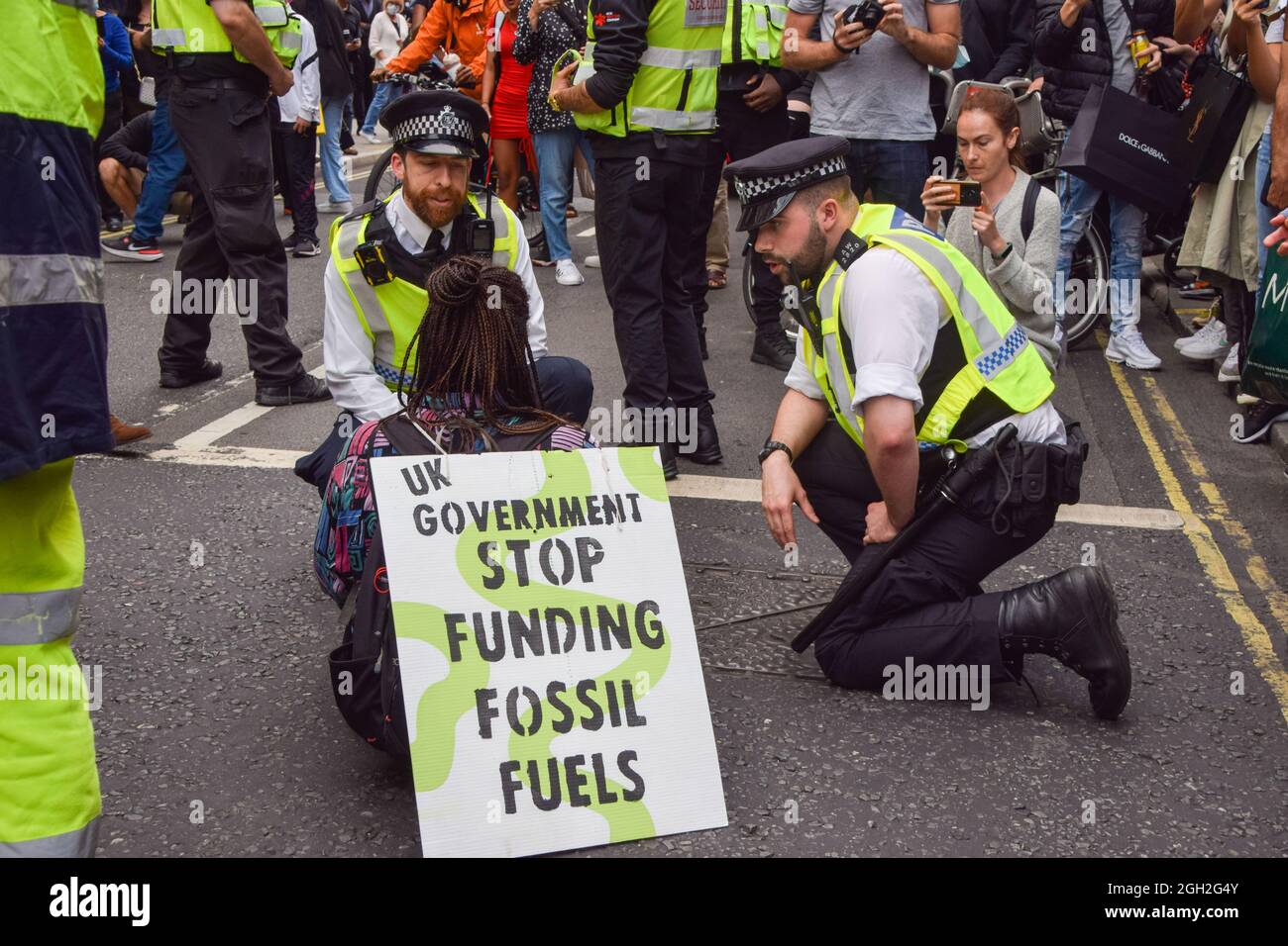 London, United Kingdom. 4th September 2021. Police talk to a protester blocking the road. A pair of Extinction Rebellion protesters blocked the traffic on Oxford Street on the final day of their two-week Impossible Rebellion campaign, calling on the UK Government to act meaningfully on the climate and ecological crisis. (Credit: Vuk Valcic / Alamy Live News) Stock Photo