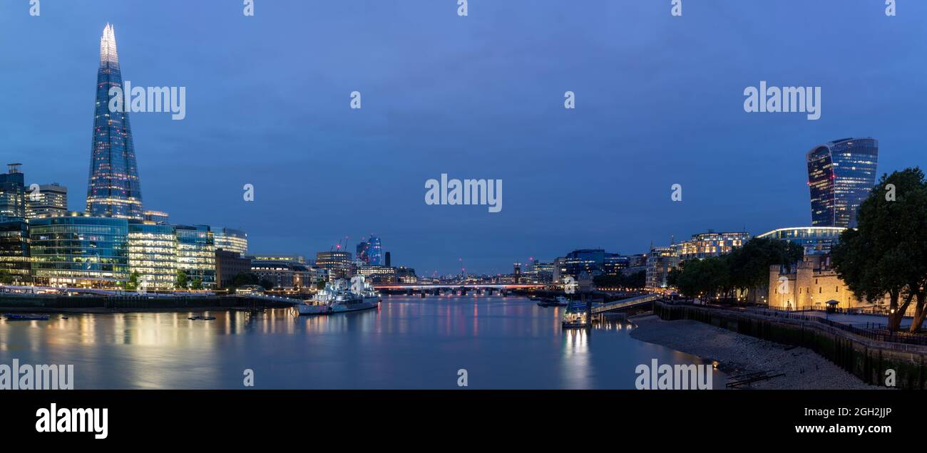 LONDON, UK - AUGUST 20, 2021:  Panorama view looking west along the River Thames with the Shard and towers in the city skyline in blue hour Stock Photo