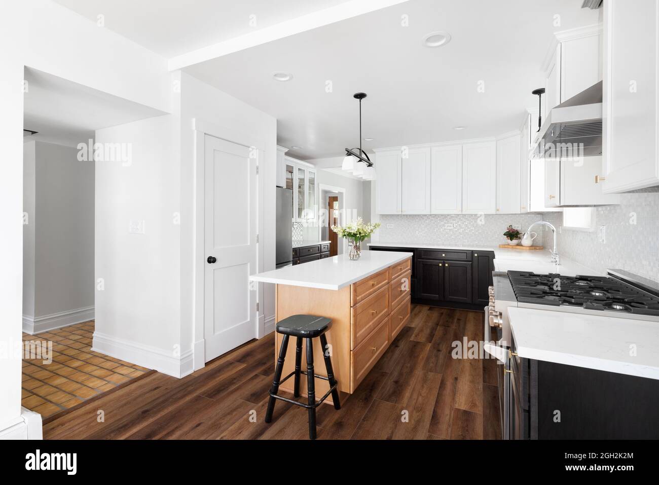 A renovated kitchen with white and wood a large island, and