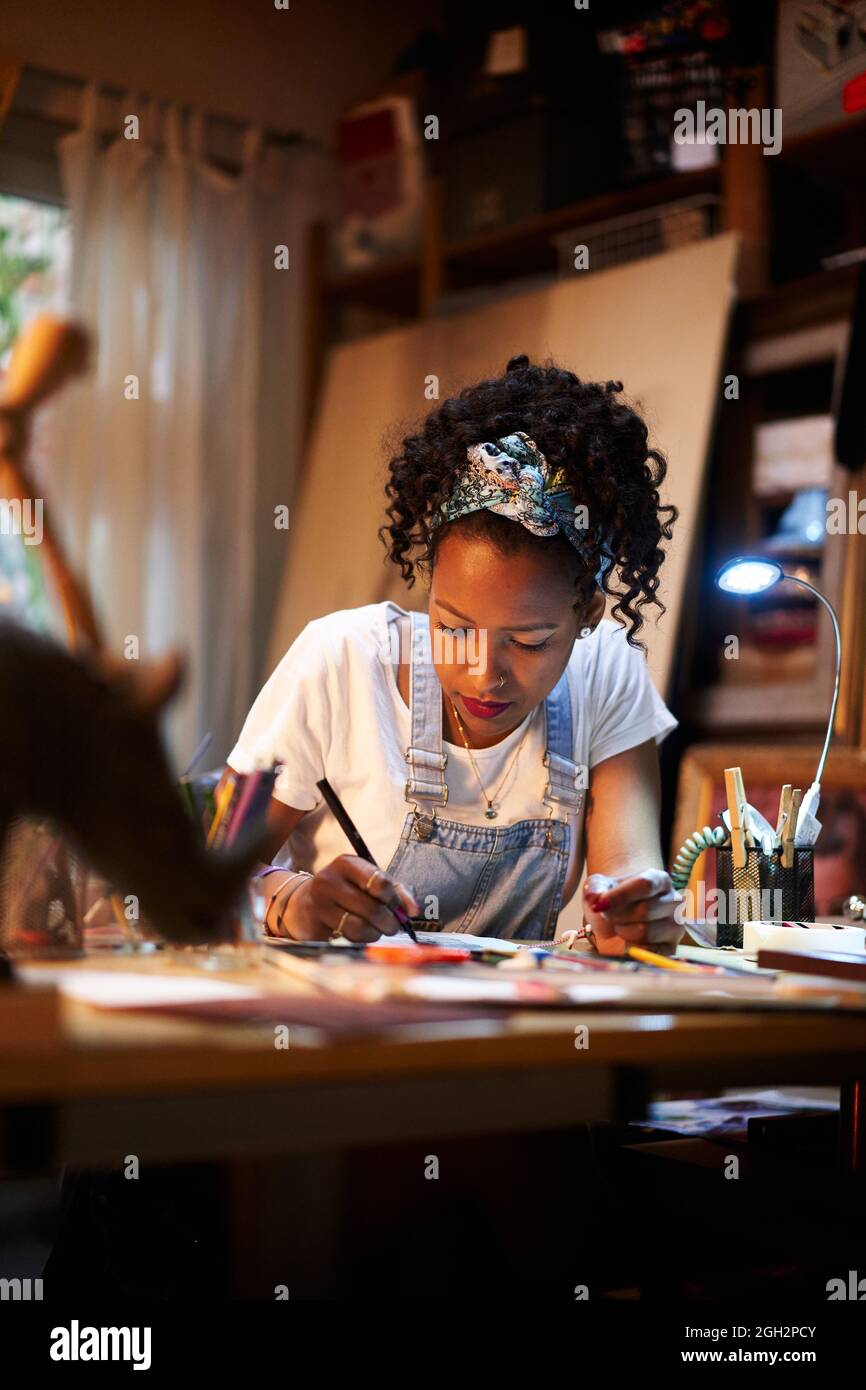 Vertical photo. Close-up of a young African-American artist at work in the studio. Creative person making art. Stock Photo