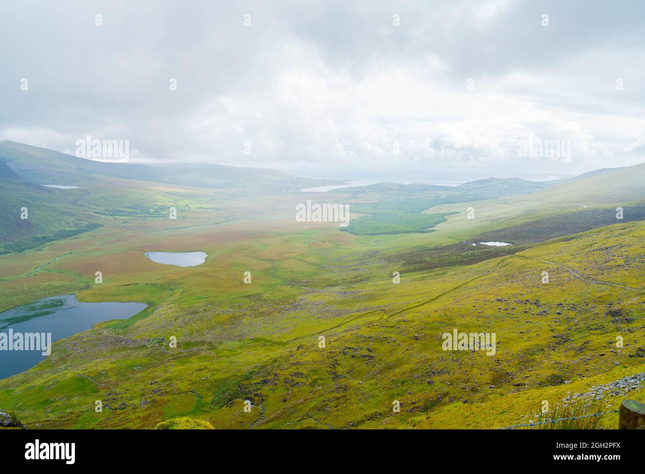 Valley fields with small lakes and dry stone walls leading through mist ...