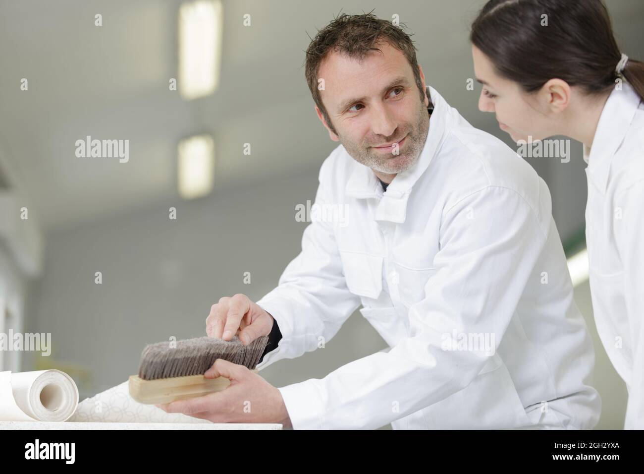 painter teaching paintbrush technique to apprentice Stock Photo