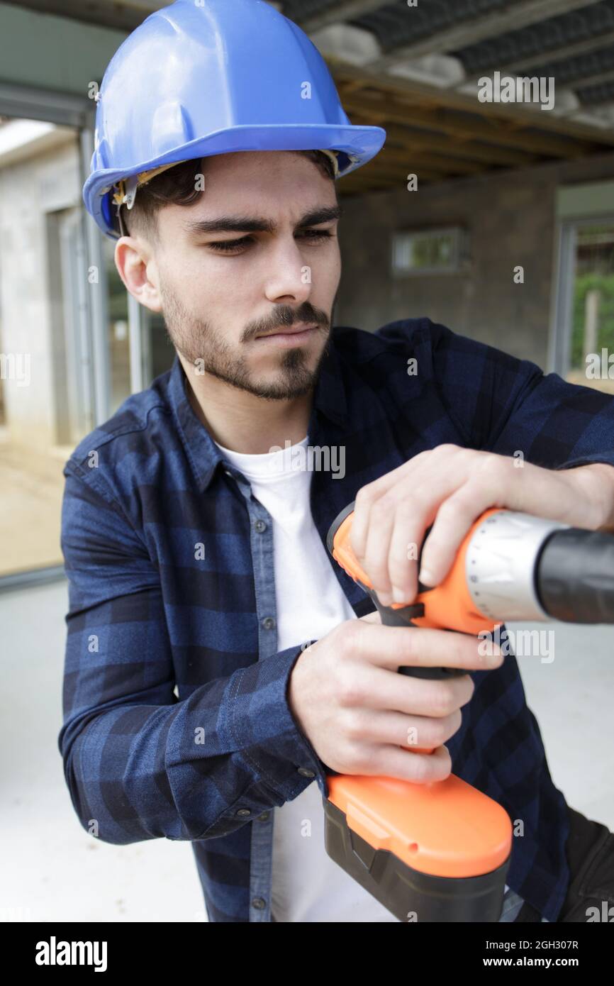young builder is drilling a wall Stock Photo