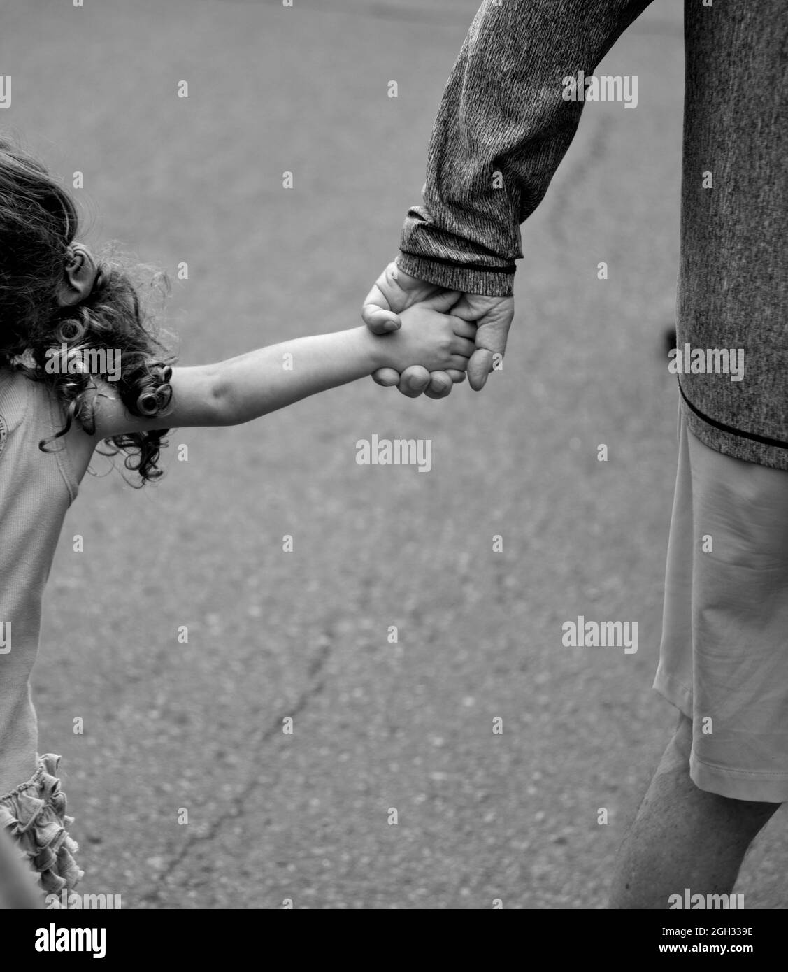 A man holds his granddaughter's hand as they walk in Santa Fe, New Mexico.s Stock Photo