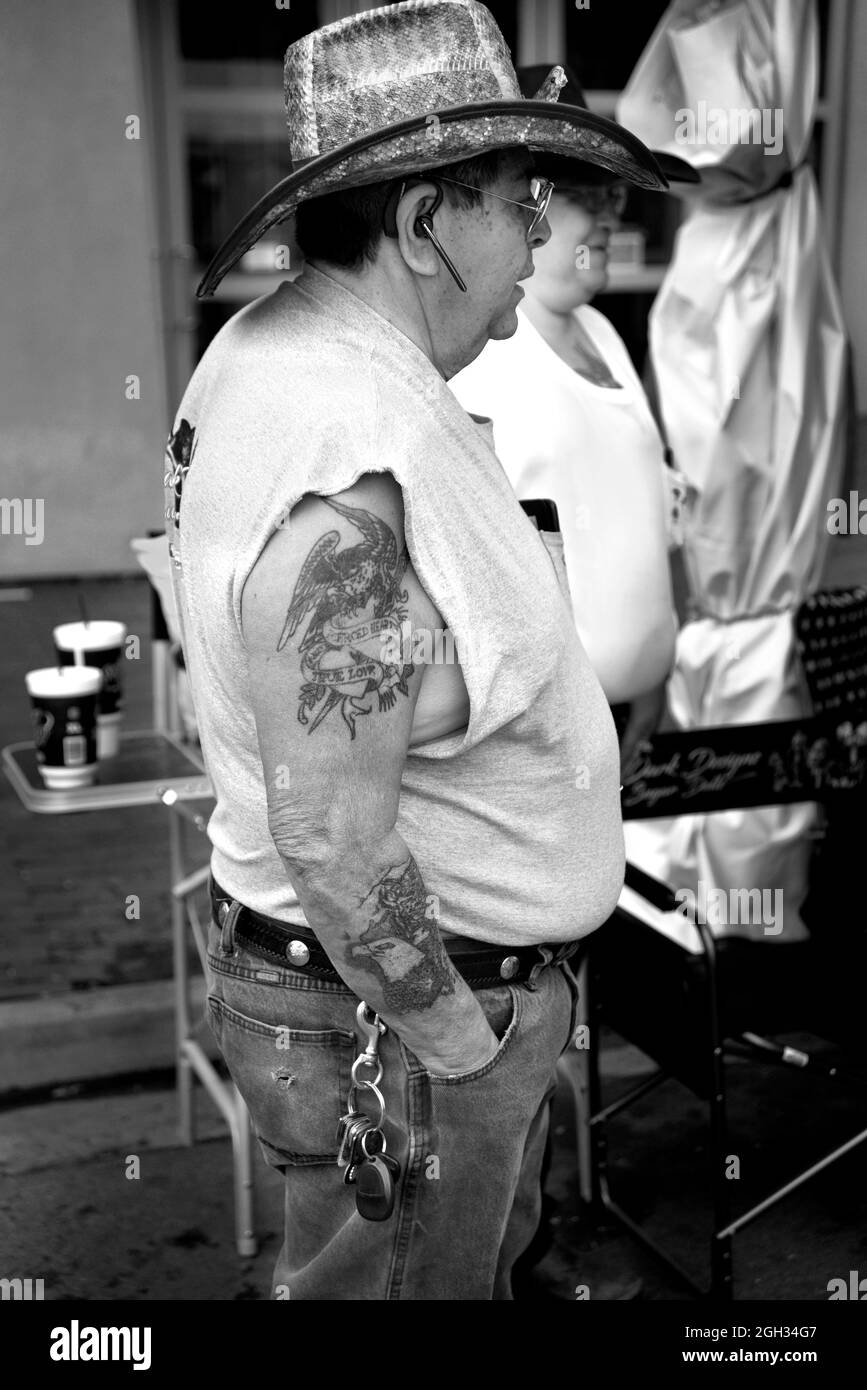 A man with tattoos on his arm stands beside an artist's booth at an outdoor art show in Santa Fe, New Mexico. Stock Photo