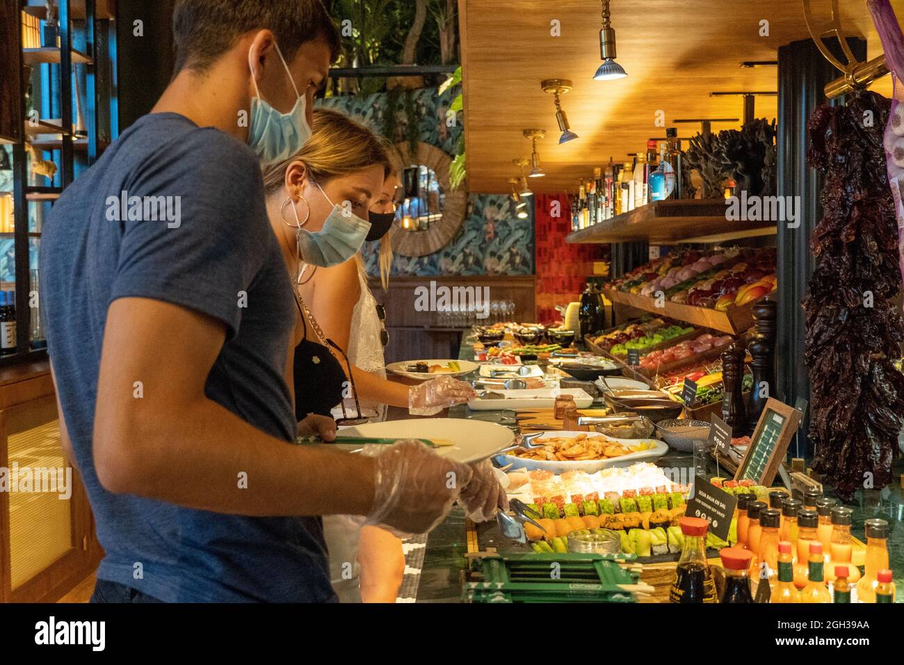 Caucasian friends with mask and plastic gloves having food in a self service restaurant Stock Photo