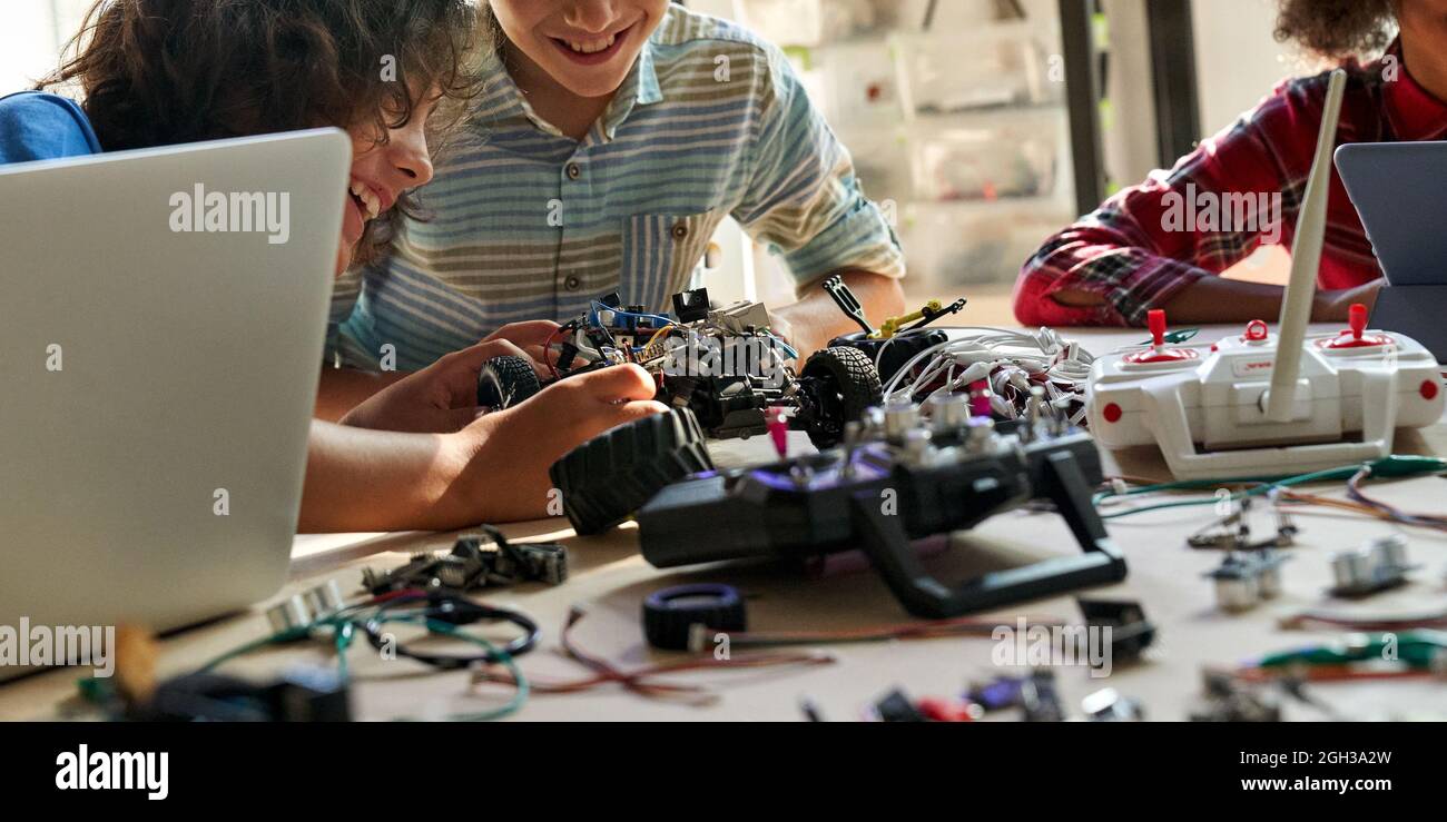 School kids boys helping building robotic car learning together at STEM class. Stock Photo