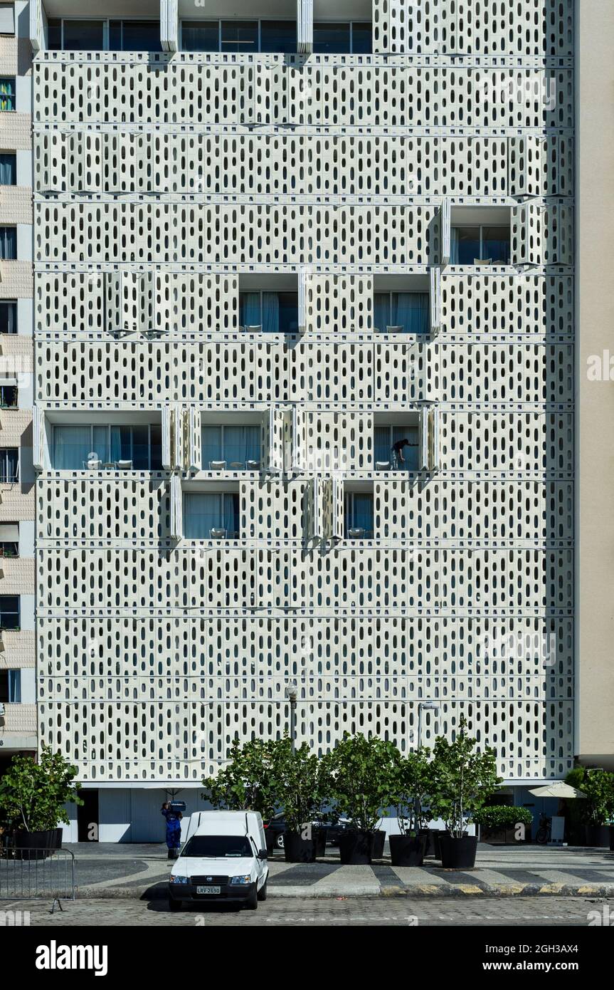 Facade of Emiliano Hotel at Atlantic Avenue - cleaning professional works in a room. The skin-like surface of the building made of  fiberglass panels creates a perforated design, ensuring guests both privacy and sea view, even when closed. Stock Photo