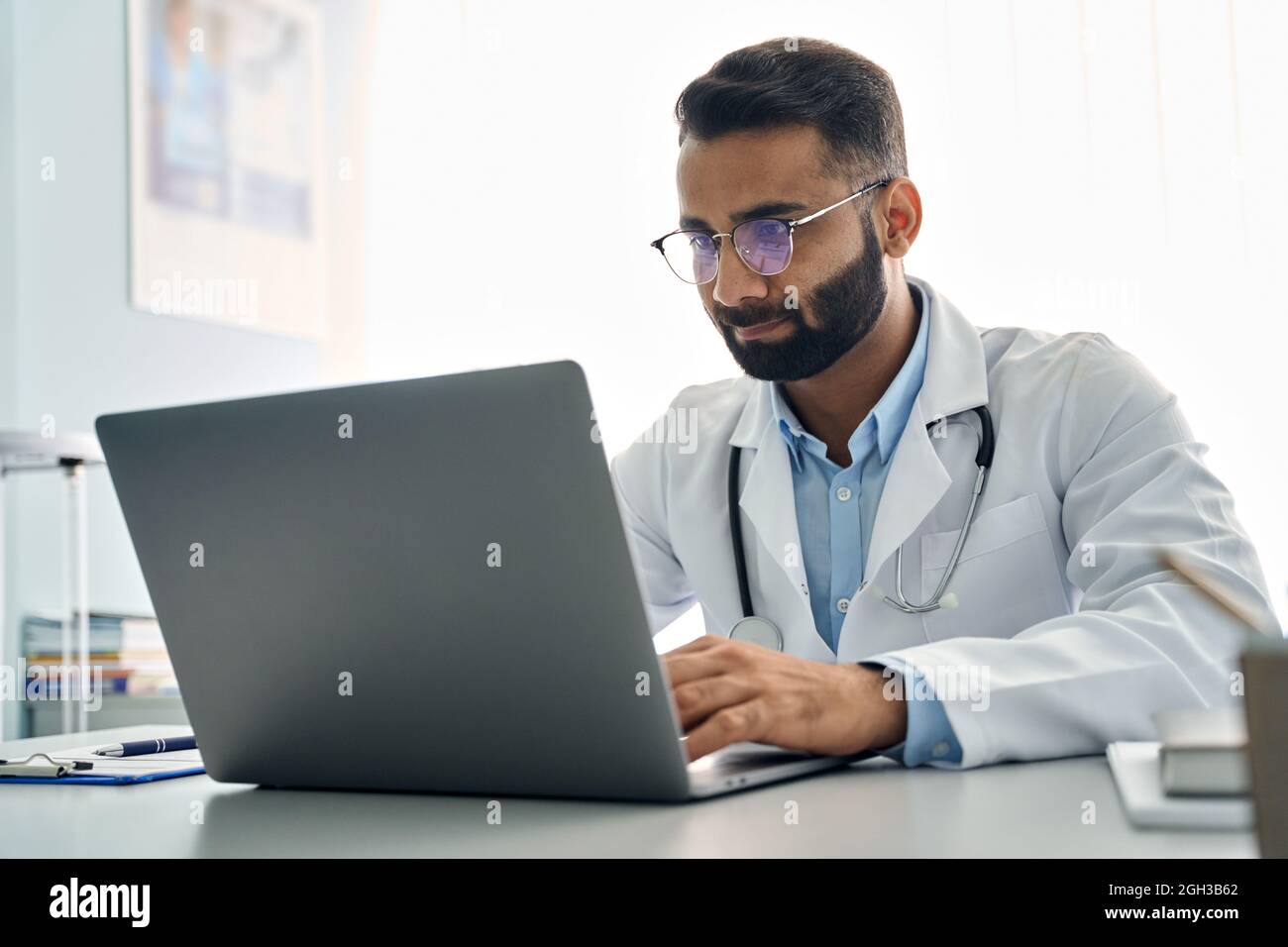 Indian male doctor using laptop computer at work in hospital. Stock Photo