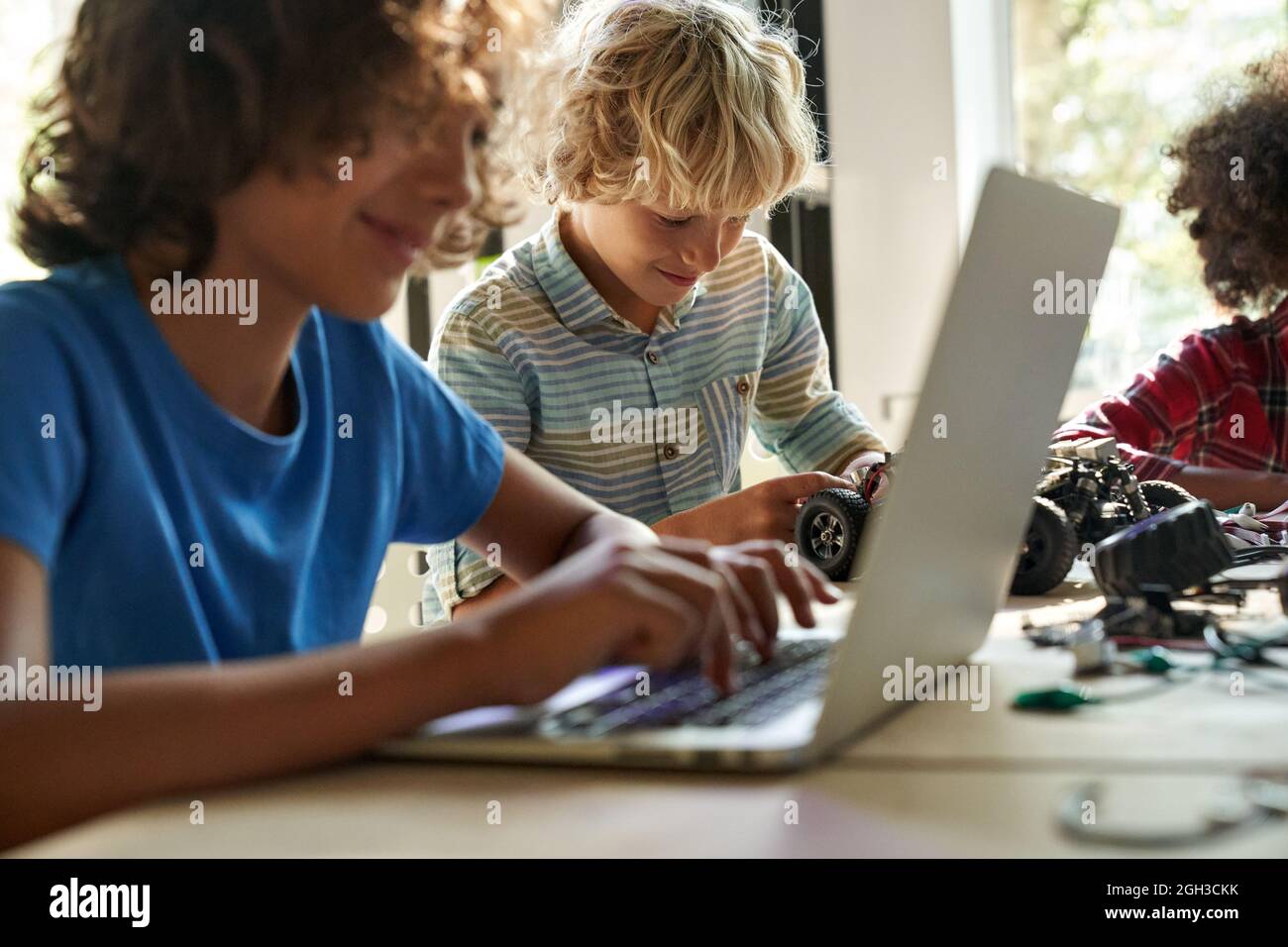 Happy school boy student making robotic car learning at STEM class. Stock Photo