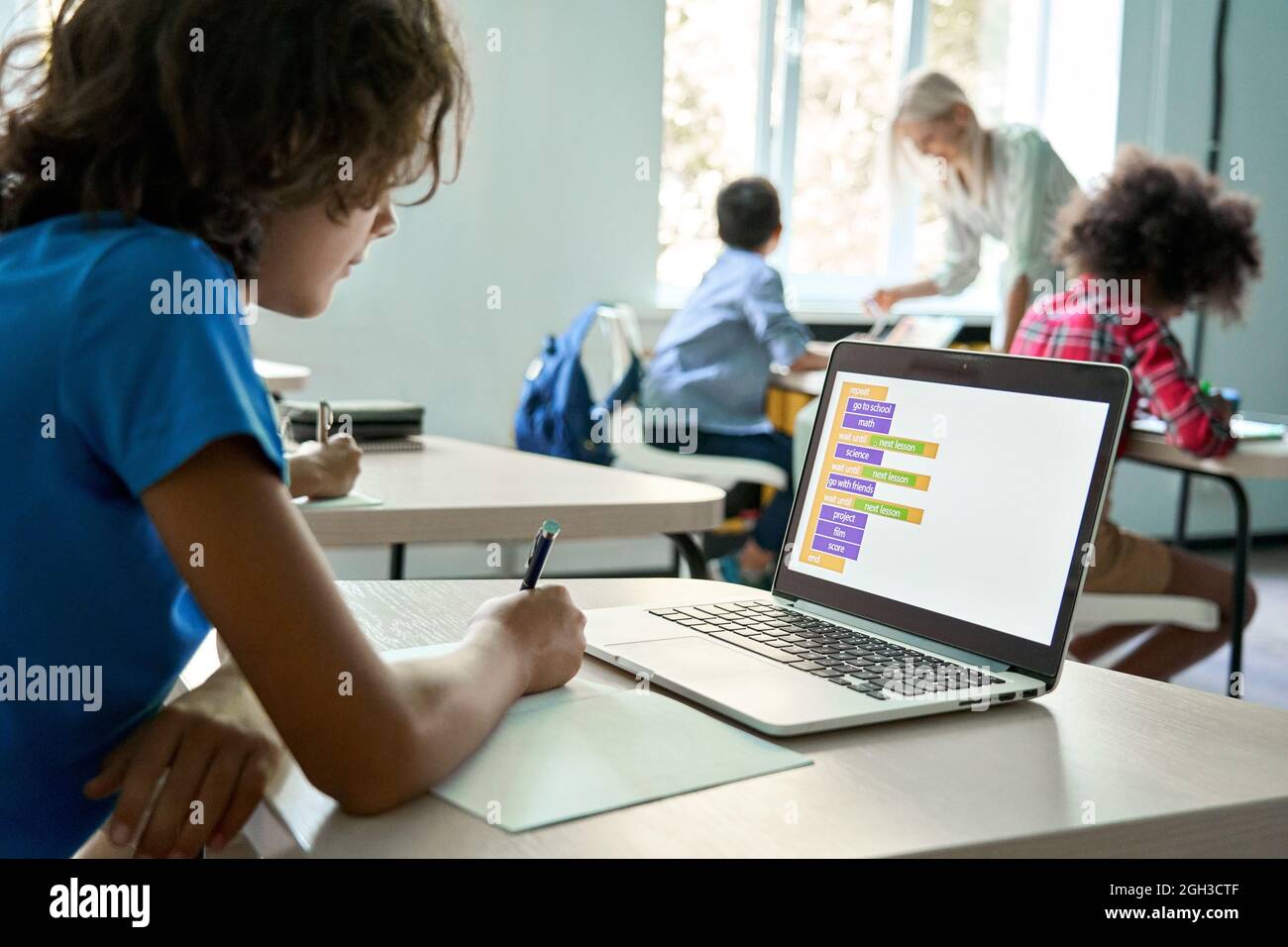Teen boy school student using laptop learning program during class in classroom. Stock Photo