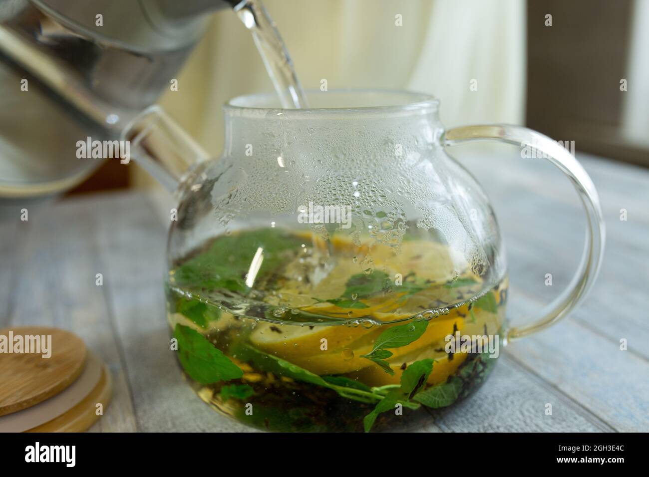 https://c8.alamy.com/comp/2GH3E4C/a-woman-pours-hot-water-into-a-kettle-with-mint-tea-and-sliced-lemon-the-process-of-making-tea-with-mint-and-lemon-healthy-food-concept-2GH3E4C.jpg