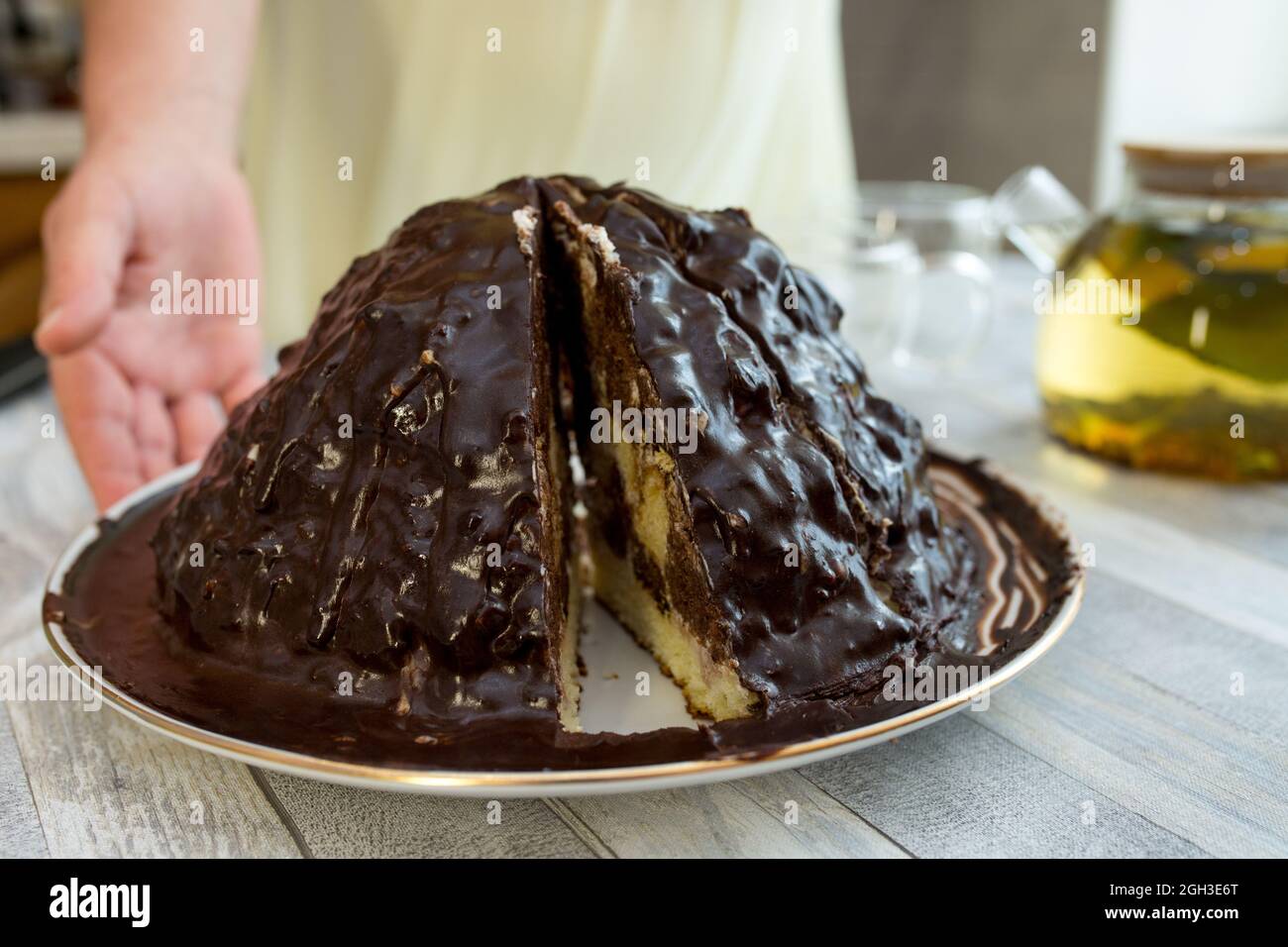A woman cuts a chocolate cake with a sharp large knife. Tea drinking with homemade sweets. Stock Photo