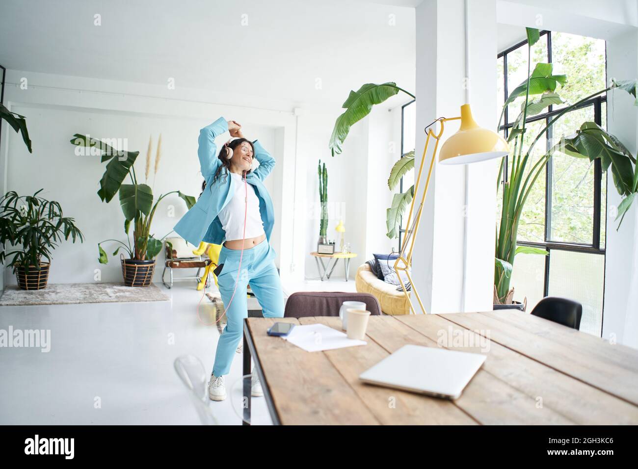 Happy cheerful young attractive business woman in formal suit dancing victory dance in home office. Female office worker having fun at work place. Stock Photo