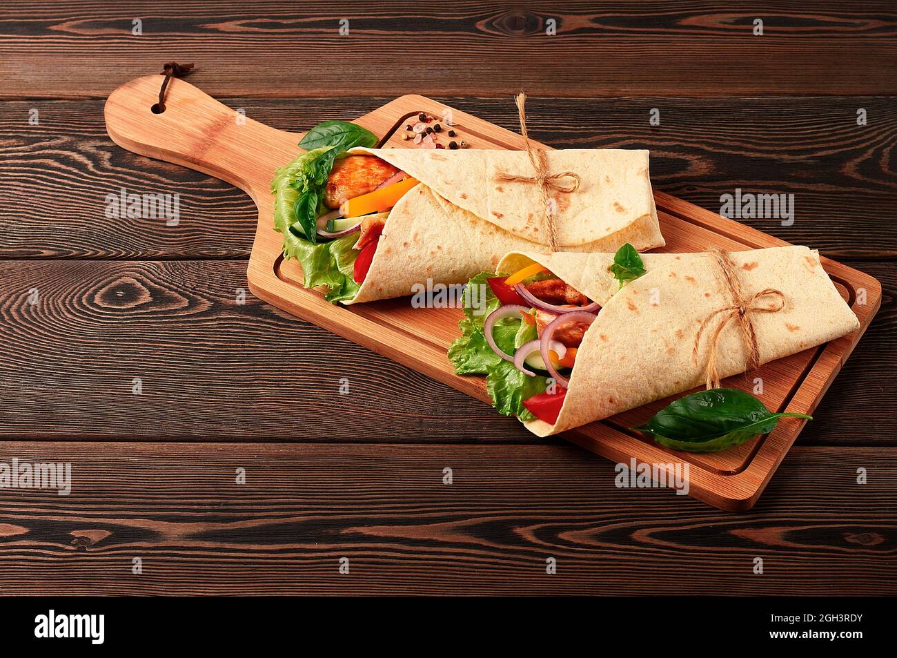 Tortilla wraps, grilled Mexican chicken with vegetables, burritos, on a wooden table, without people, Stock Photo