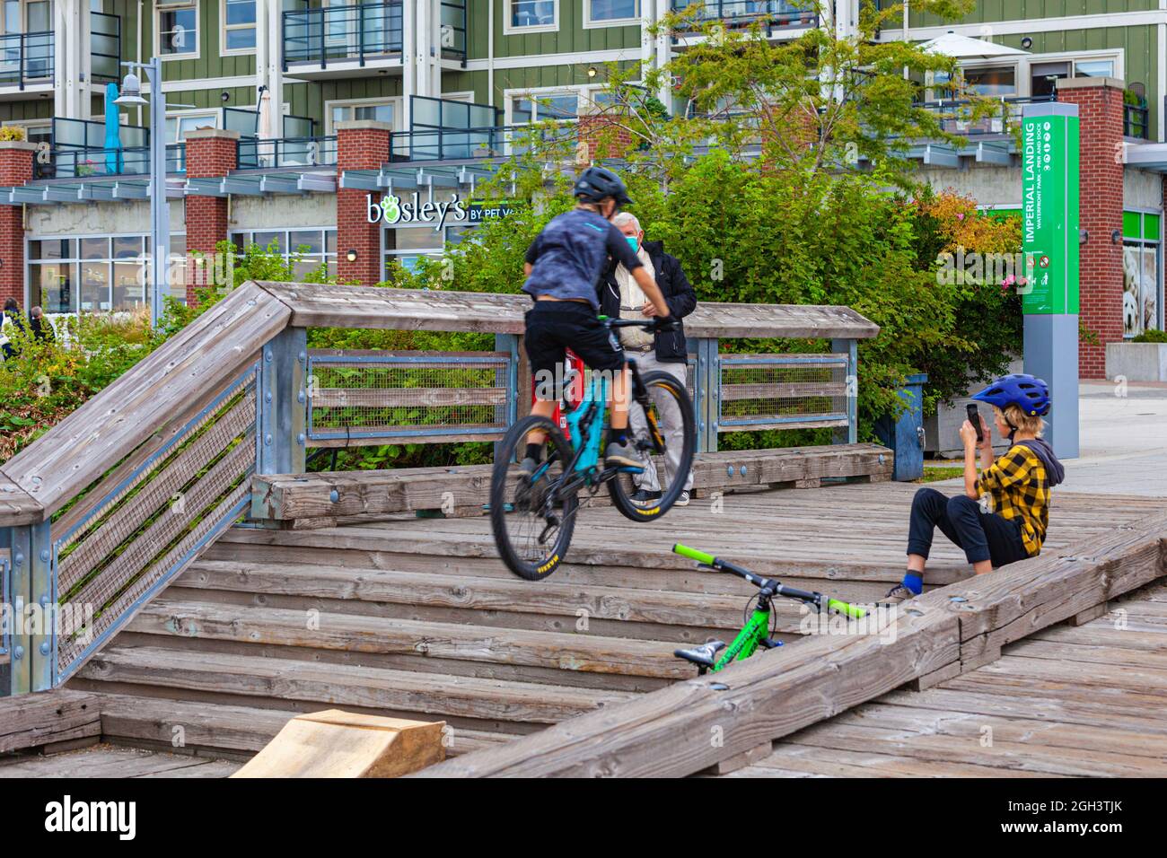 Young boys stunt riding on their mountain bikes along the Steveston waterfront in British Columbia Canada Stock Photo