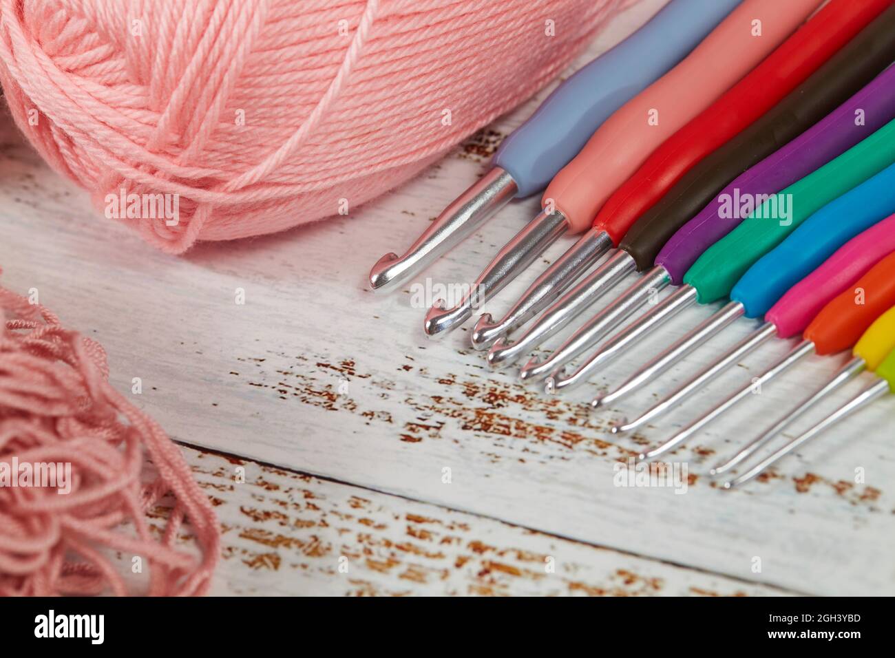 knitting pink crochet hooks and woolen thread on a blue background