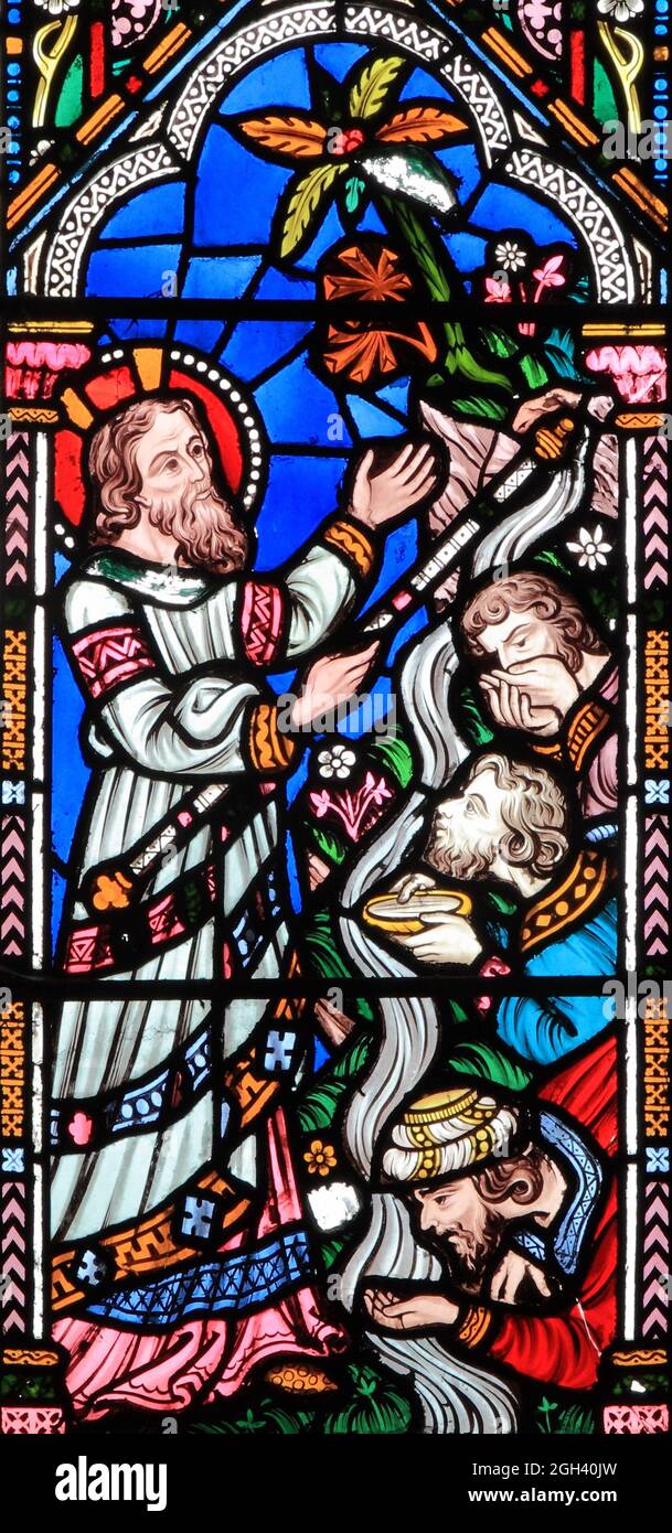 Moses strikes rock, with stick, water flows from rock, men drink the water, stained glass, by Frederick Preedy, 19th century, Snettisham, Norfolk Stock Photo