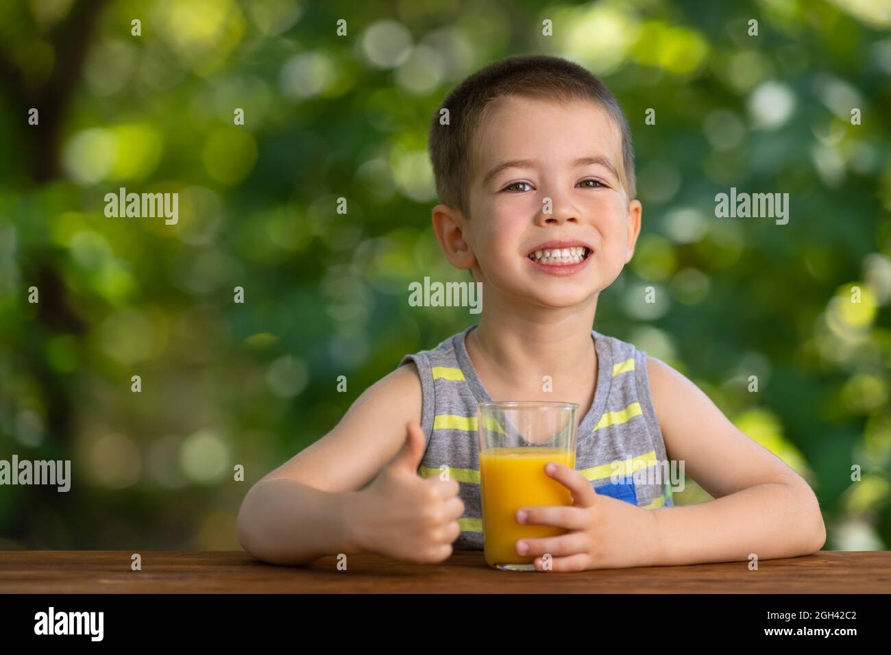 little boy holding glass of juice and showing thumbs up Stock Photo