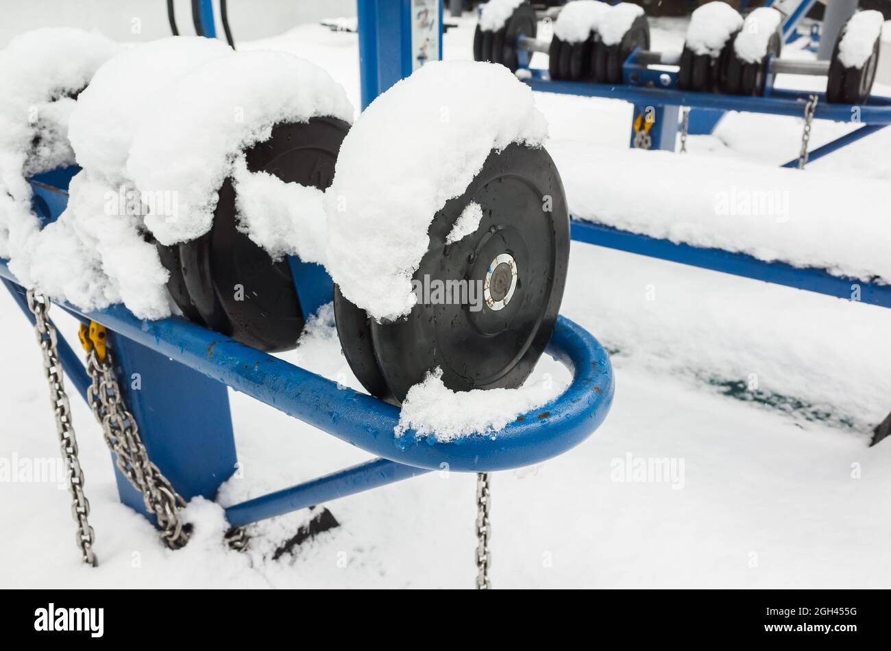 Dumbbells with snow, an outdoor gym equipment. Fitness zone of a public park open and free for visiting during all seasons Stock Photo