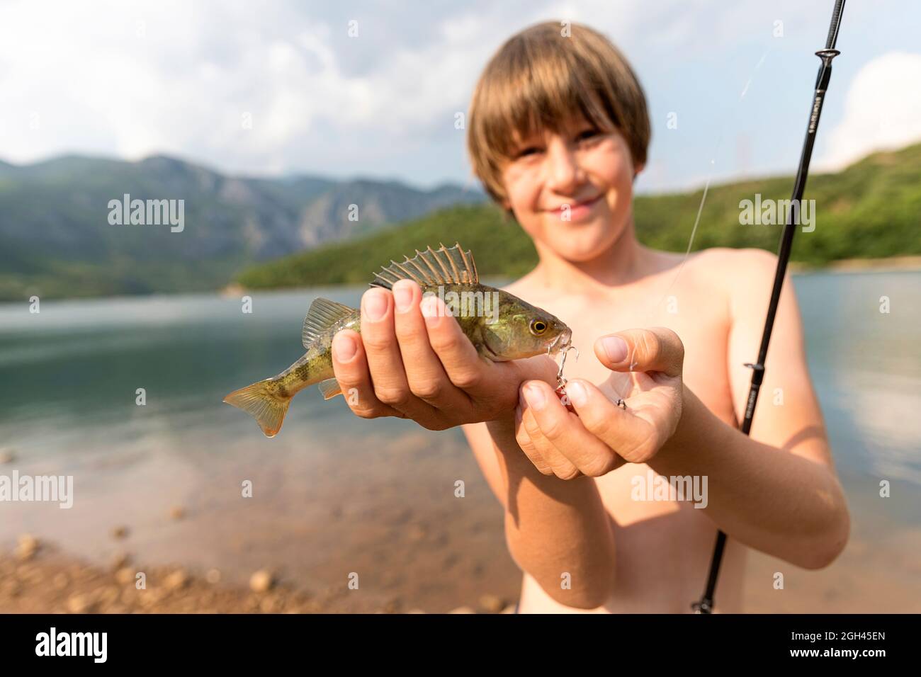 Boy showing a fish that he caught in Vau Dejes reservoir on Drin river in Albania Stock Photo