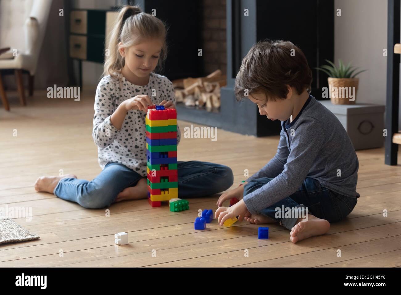 Two sibling children completing tower model form plastic building blocks Stock Photo