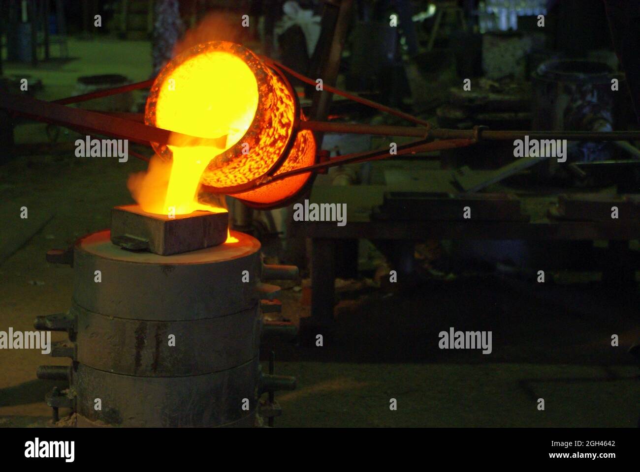 Pouring molten metal from crucible into moulding box Stock Photo