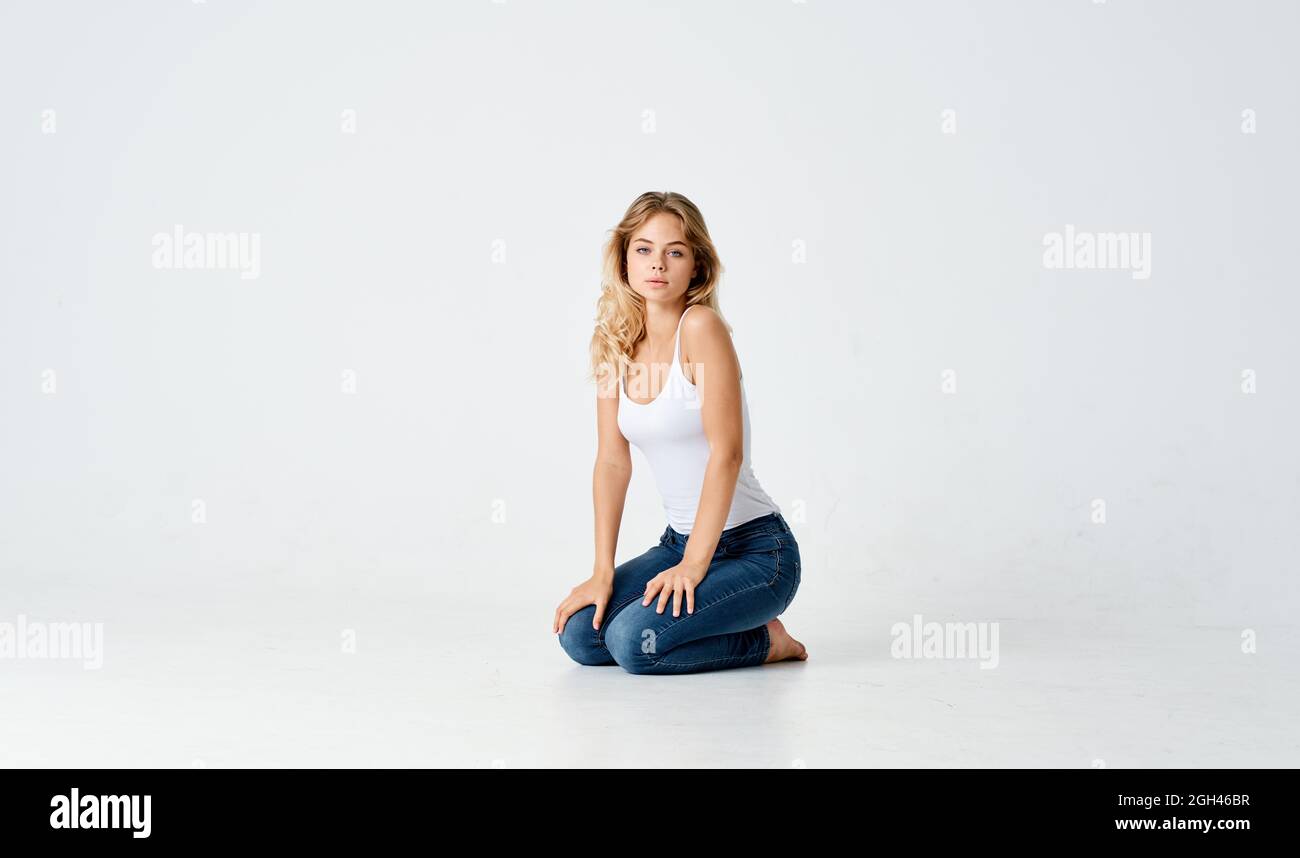 pretty blonde in jeans sitting on the floor isolated background Stock ...