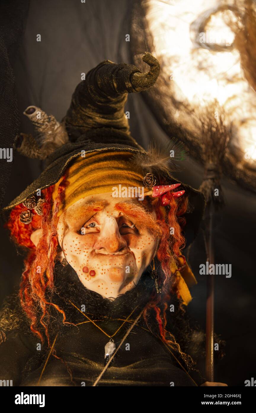 Halloween decorations, Spooky, evil, creepy, horrible, terrifying, good witch with freckles, warts, mushrooms, red hair and a broom in an old witch hat and rags in the moonlight Stock Photo