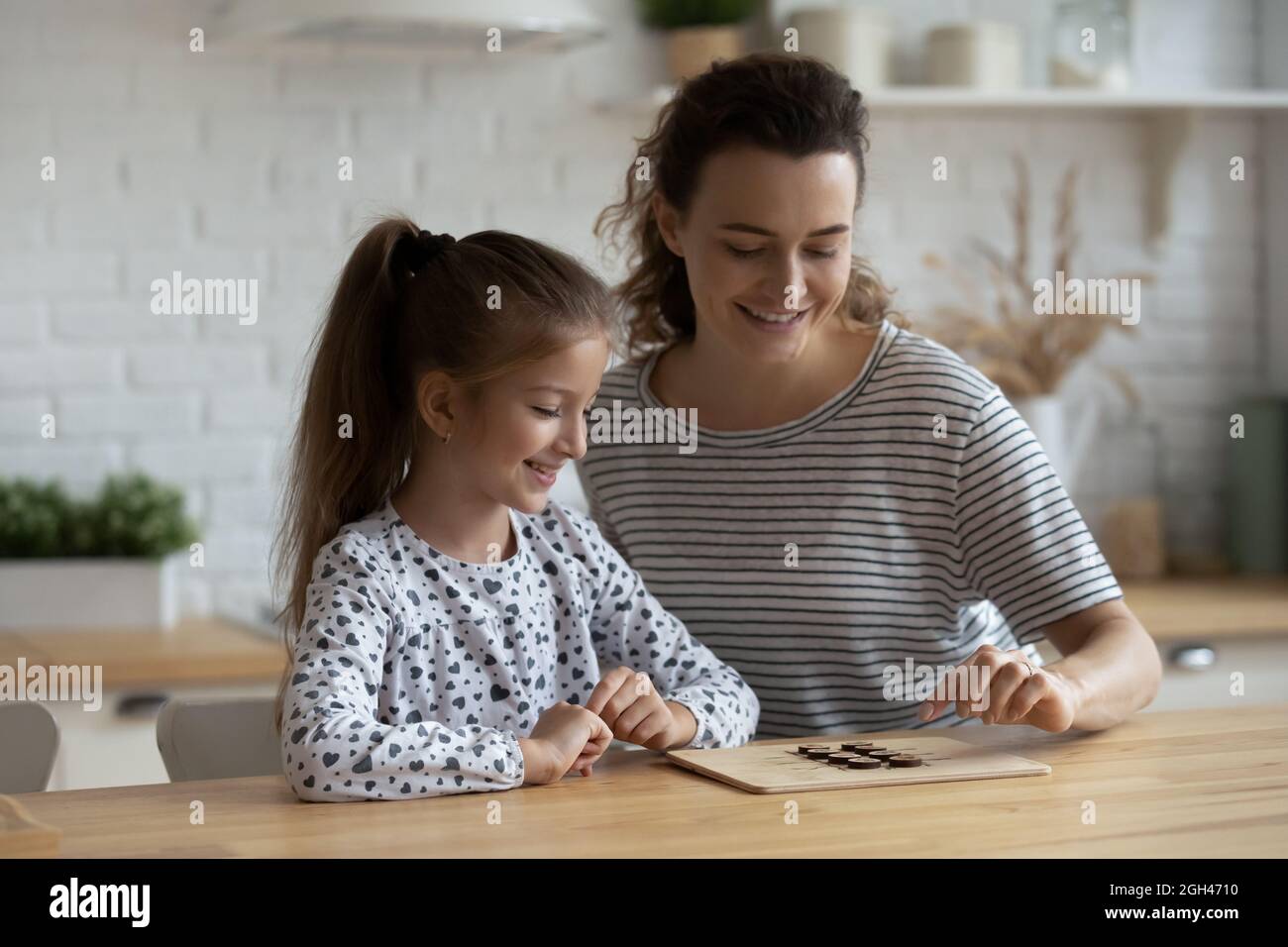 Happy engaged mom and daughter kid enjoying in board game Stock Photo