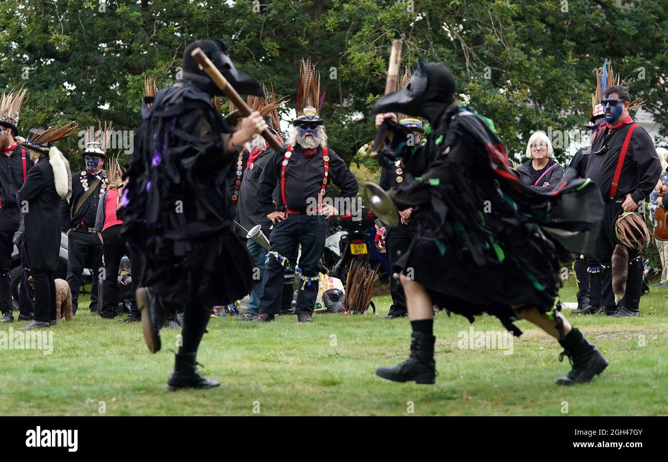 Members of the Hook Eagle Border Morris group look on as the Huginn and Muninn Bedlam morris group perform in Hartley Wintney in Hampshire. The Morris group joined the Hook Eagle Border Morris group to celebrate their 30th birthday celebrations as they 'Morris bombed' locations around the village during the Hartley Wintney festival. Picture date: Saturday September 4, 2021. Stock Photo