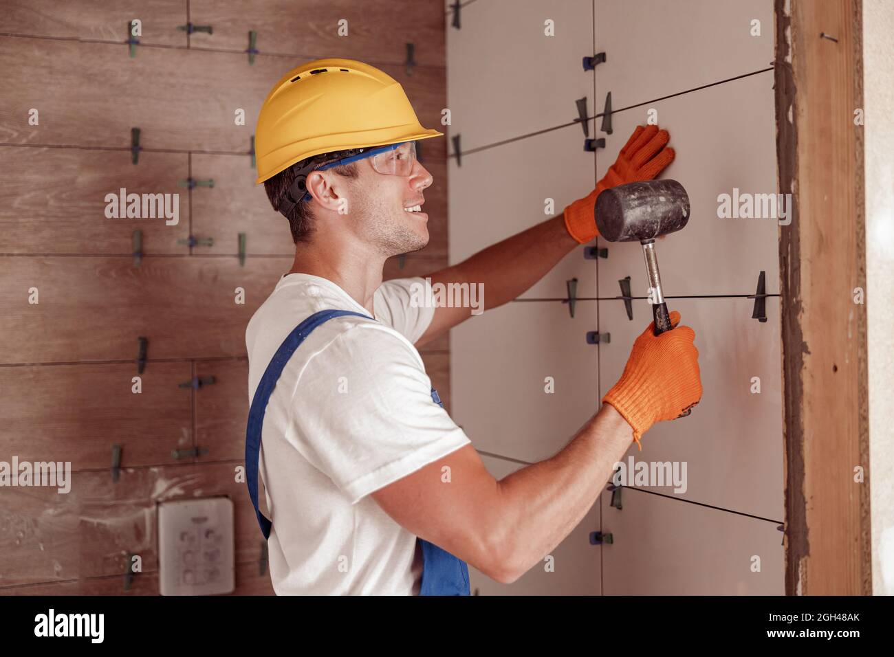 Male builder installing ceramic wall tile in house Stock Photo Alamy