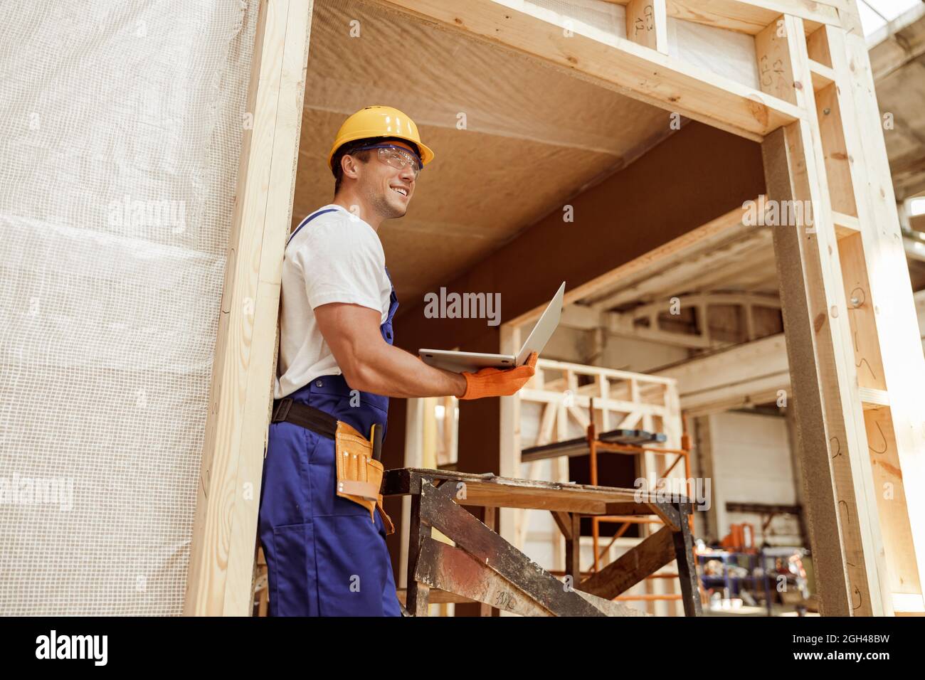Joyful male builder using laptop at construction site Stock Photo
