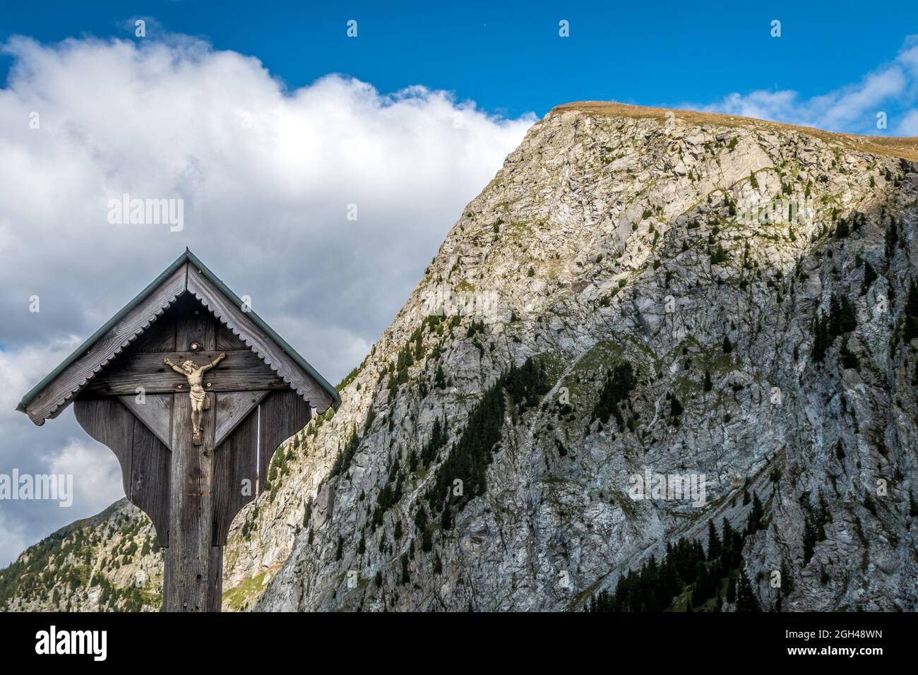 Wood crucified Christ with cross and the Ifinger peak (PIcco Ivigna) in South Tyol . Südtirol - Trentino Alto Adige - near Merano - Meran Italy Europe Stock Photo