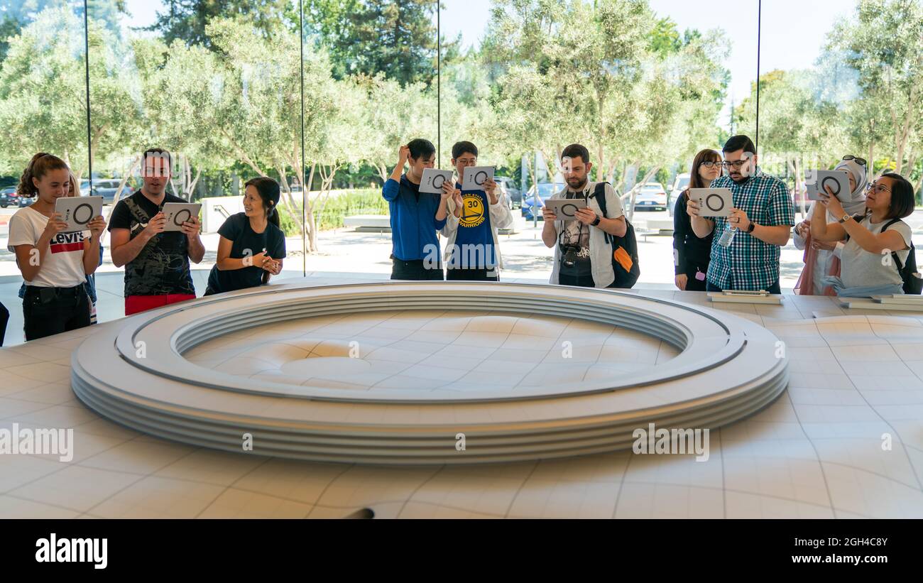 Cupertino, CA, USA - August 2019: Apple Store Cupertino with people looking at Infinite Loop Apple Headquarters through virtual reality using iPad tab Stock Photo