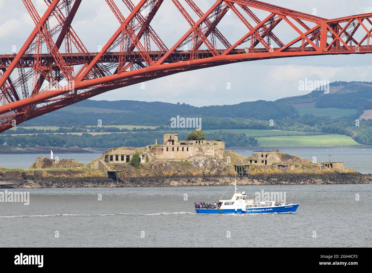 Forth Tours boat - MV Forth Belle - passing by Inchgarvie and the Forth Rail Bridge in the Firth of Forth, Queensferry, Edinburgh, Scotland, UK Stock Photo