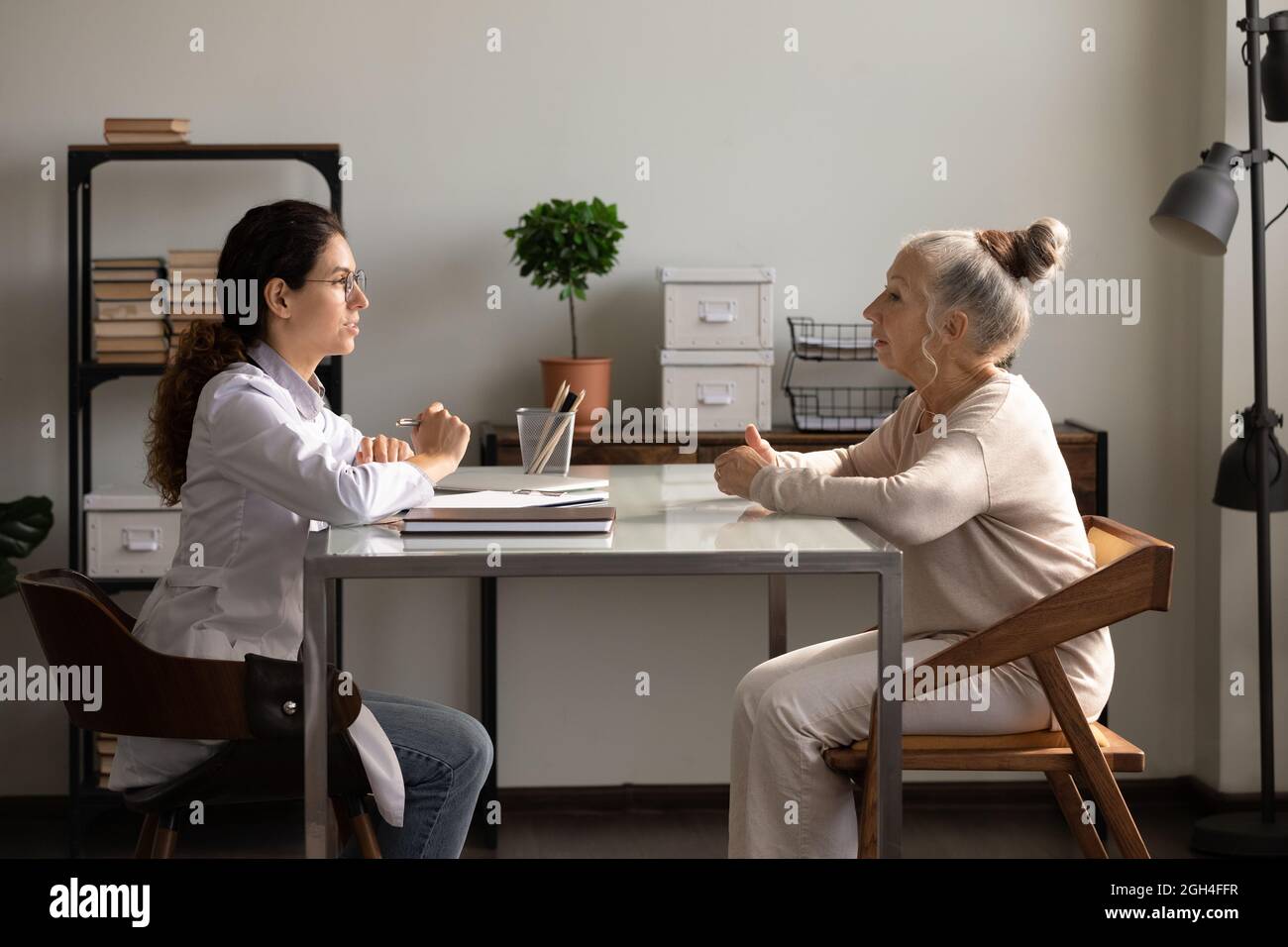 Positive doctor and old patient meeting and talking in office Stock Photo
