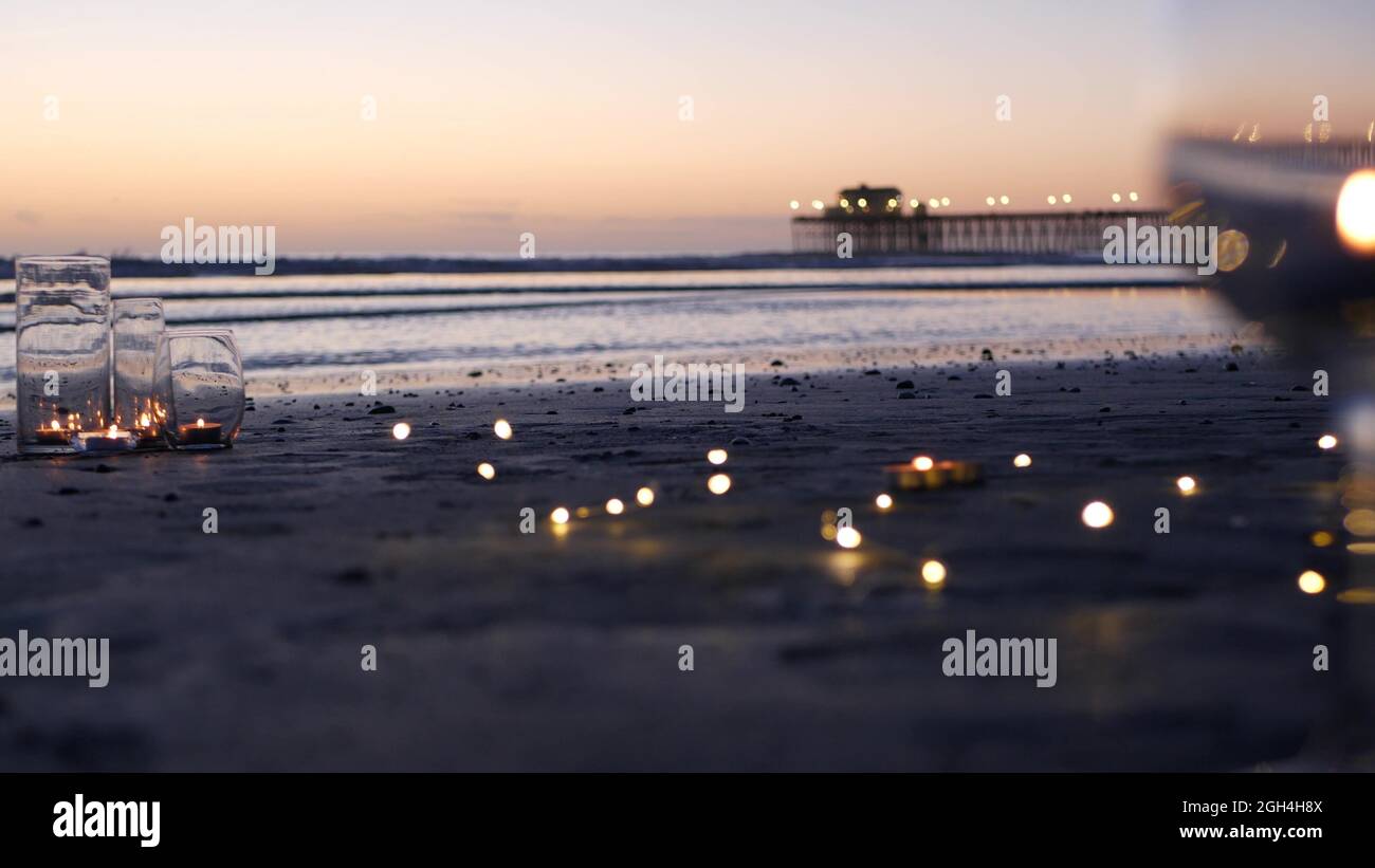 Candle flame lights in glass, romantic beach date, California ocean ...