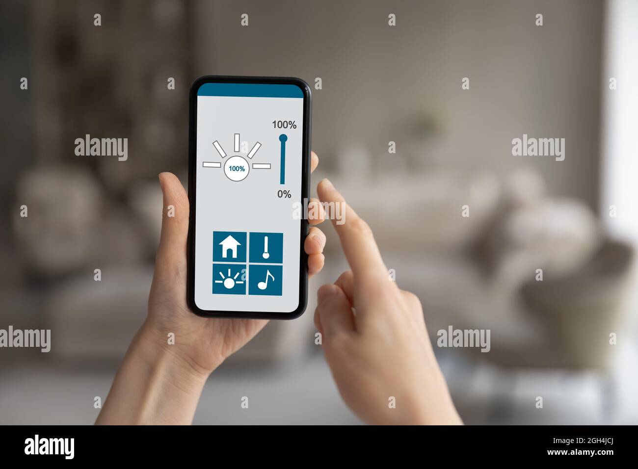 Young woman holding telephone with smart home app on screen. Stock Photo
